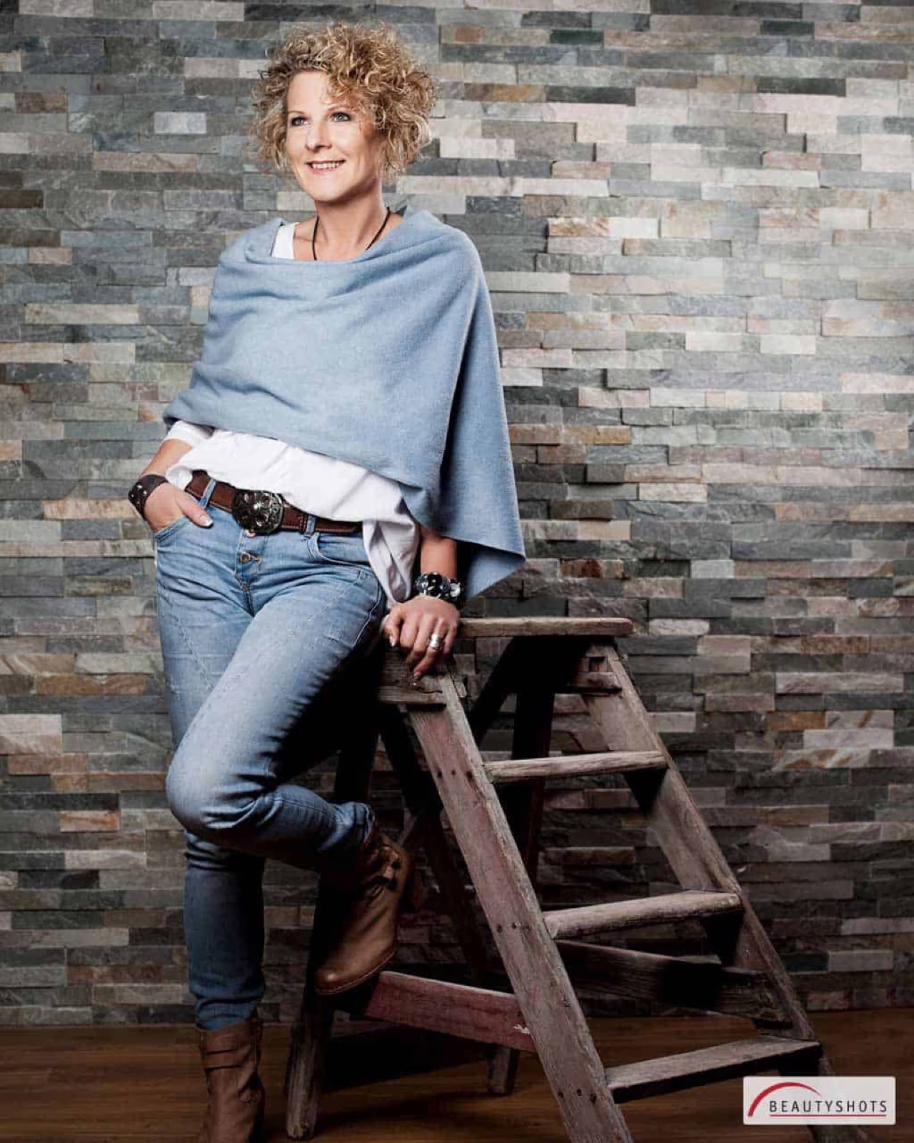 Frau in Jeans auf einer Leiter vor Backsteinwand – urbanes Beauty-Fotoshooting in Hamburg