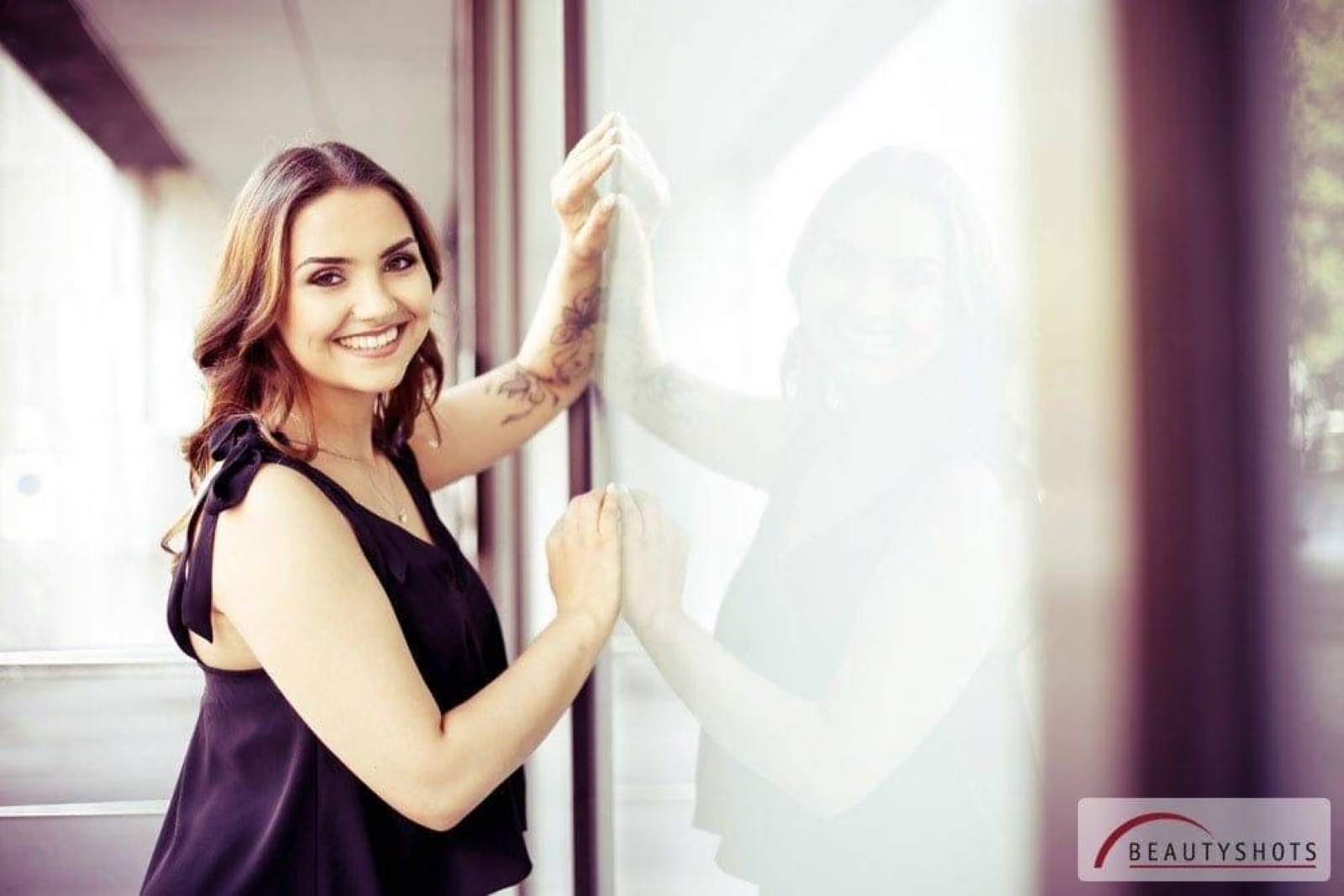 Lächelnde Frau lehnt an einer hellen Wand – Pretty Woman Fotoshooting bei BEAUTYSHOTS Fotostudio Hamburg