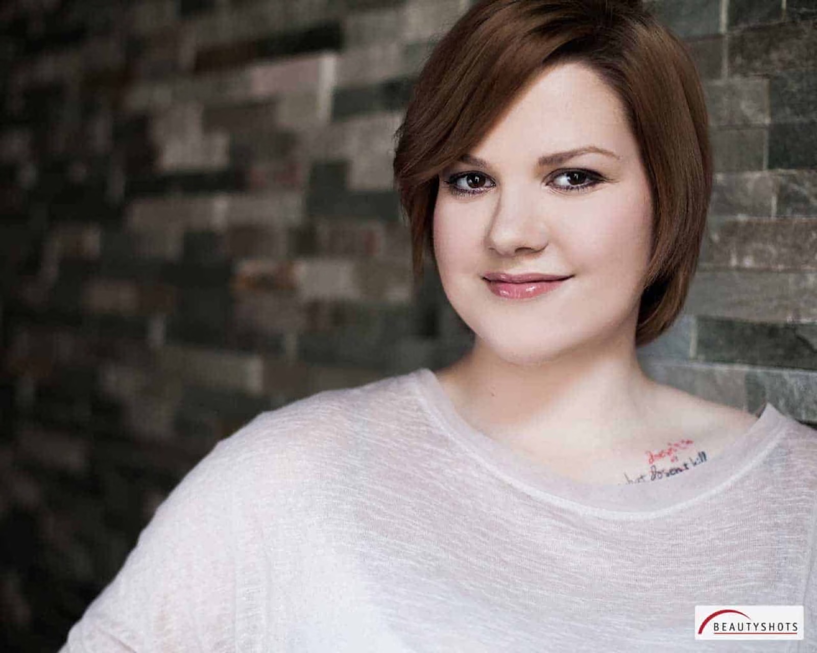 Porträt einer Frau mit kurzem Haar vor Steinwand – natürliches Beauty Shooting