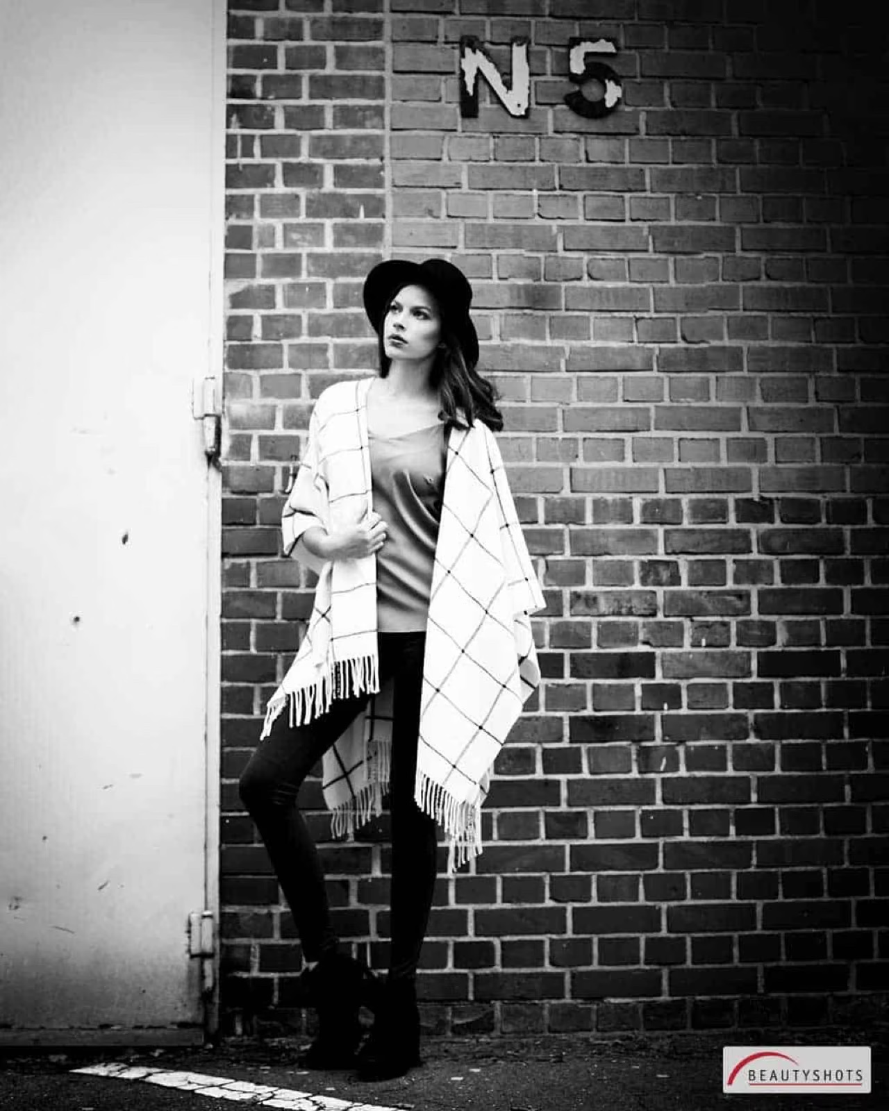 Schwarzweiß-Aufnahme einer jungen Frau vor Backsteinwand – urbanes Beauty Shooting im Fotostudio Hamburg