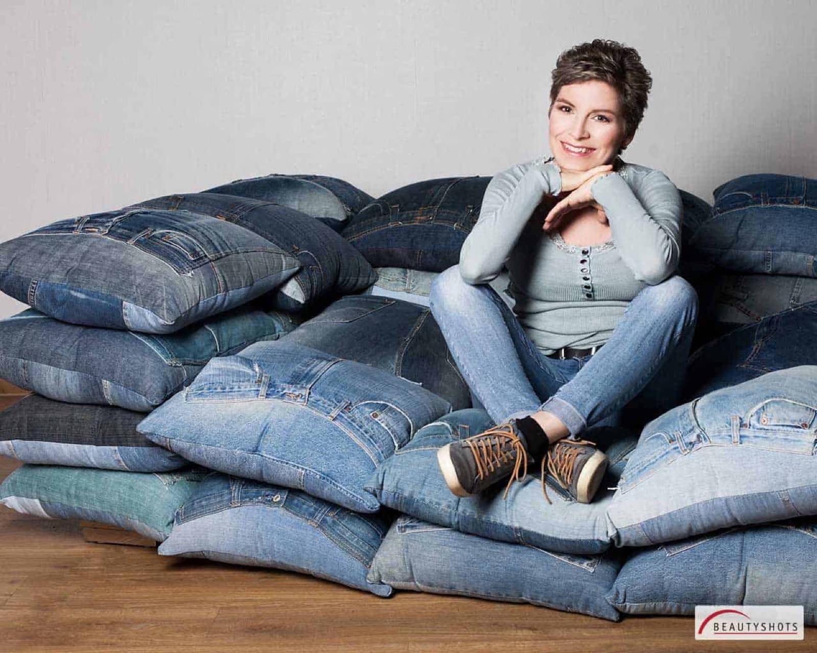 Frau entspannt auf Kissen im Studio – emotionales Beauty Shooting