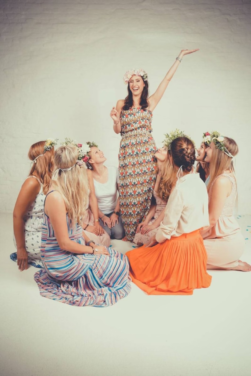 Foto von einer JGA-Gruppe die um die zukünftige Braut herum sitzt vor einem weißen Hintergrund bei einem Junggesellinnen-Fotoshooting beim Beautyshots Fotostudio in Hamburg