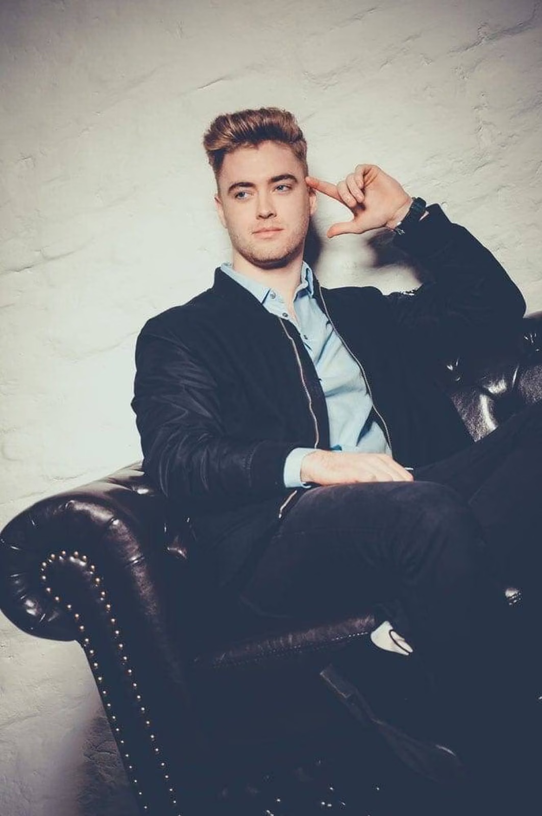 Mann im eleganten Outfit auf Ledersessel – modernes Fashion- und Männer-Fotoshooting