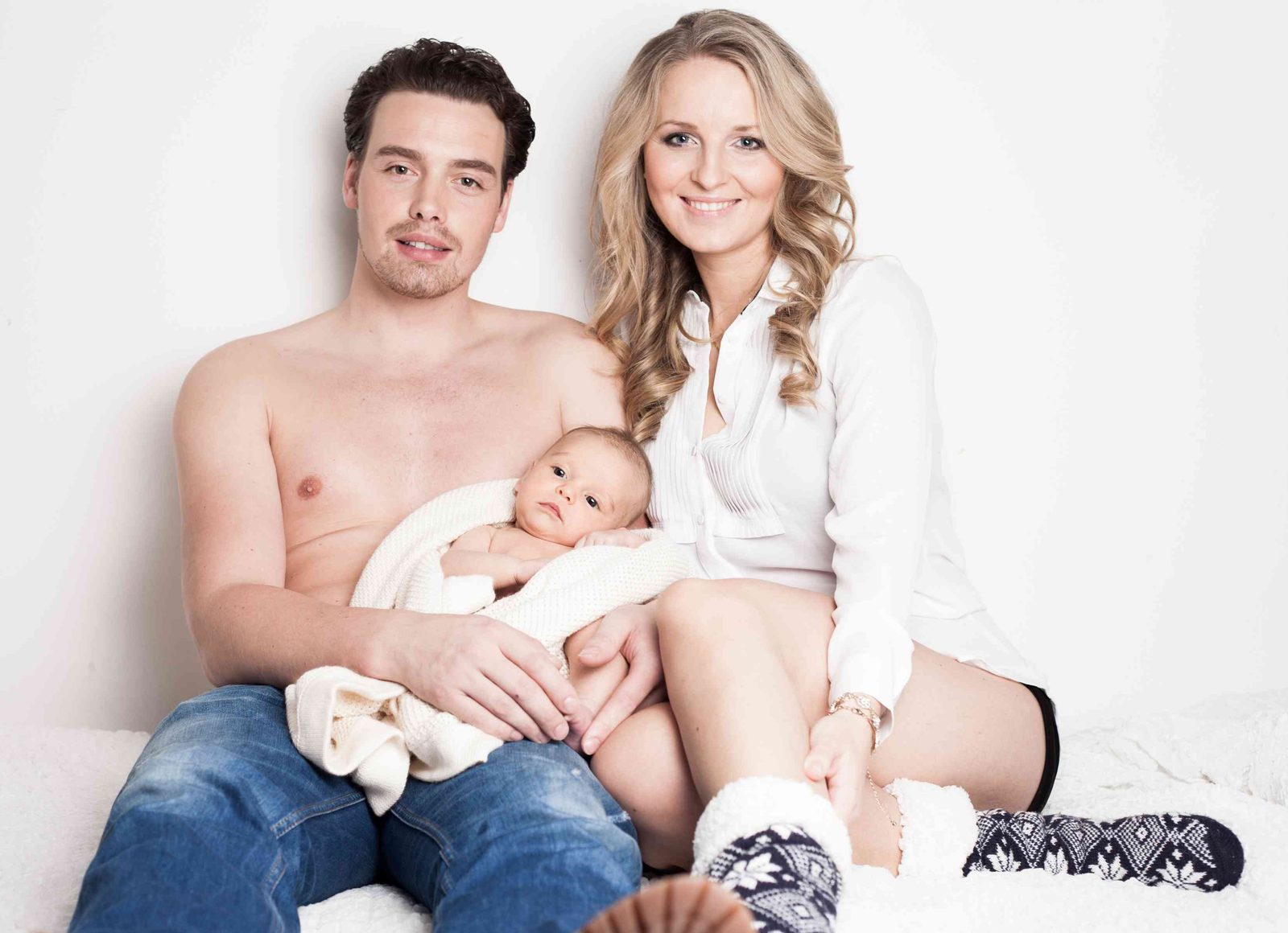 Parents holding their newborn baby in a bright studio setting