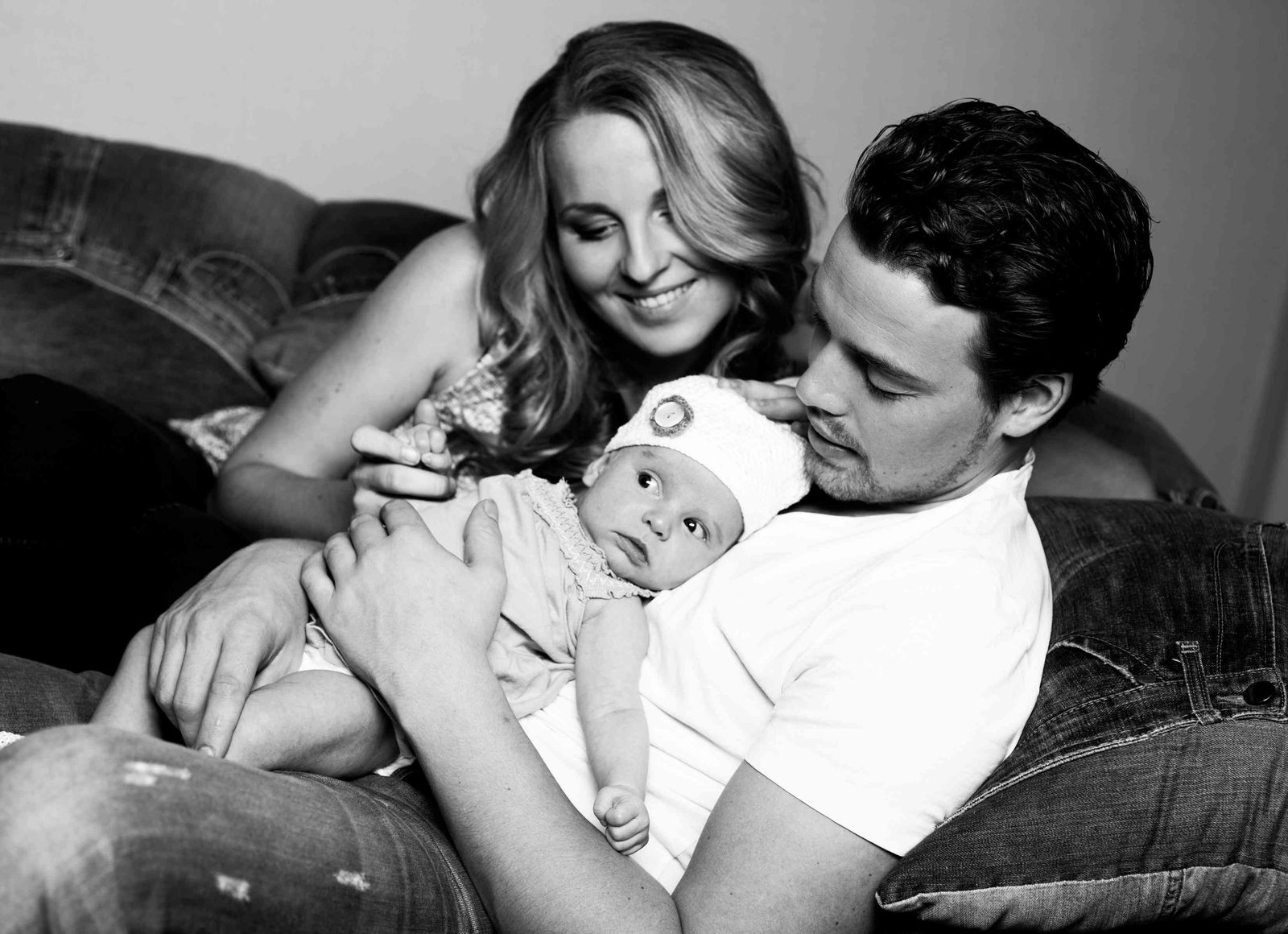 Parents smiling down at their newborn on a couch — Hamburg family photo