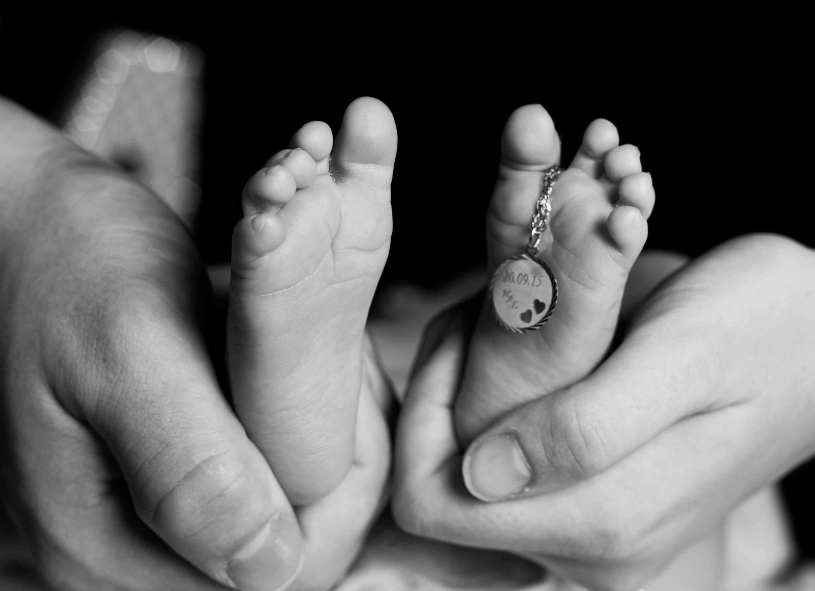 Babyfüße in Elternhänden mit graviertem Anhänger – Fotostudio in Hamburg