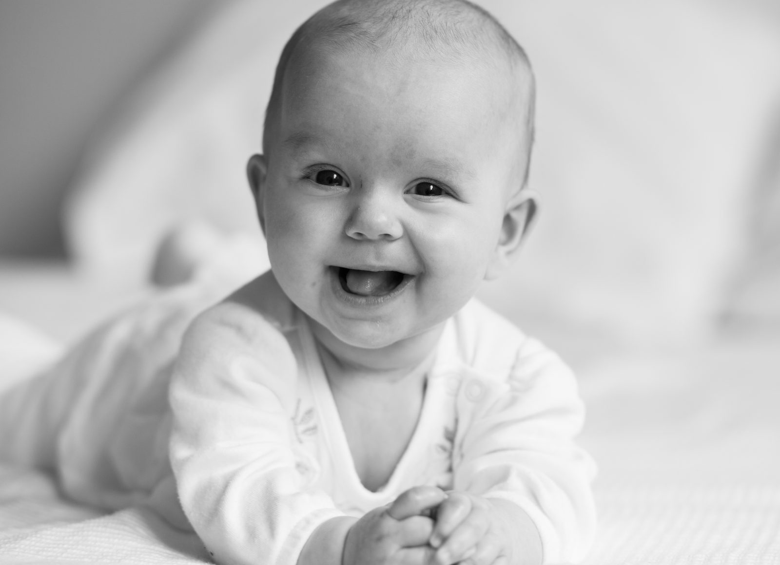 Lachendes Baby in Schwarz-Weiß auf weicher Decke – Fotoshooting in Hamburg