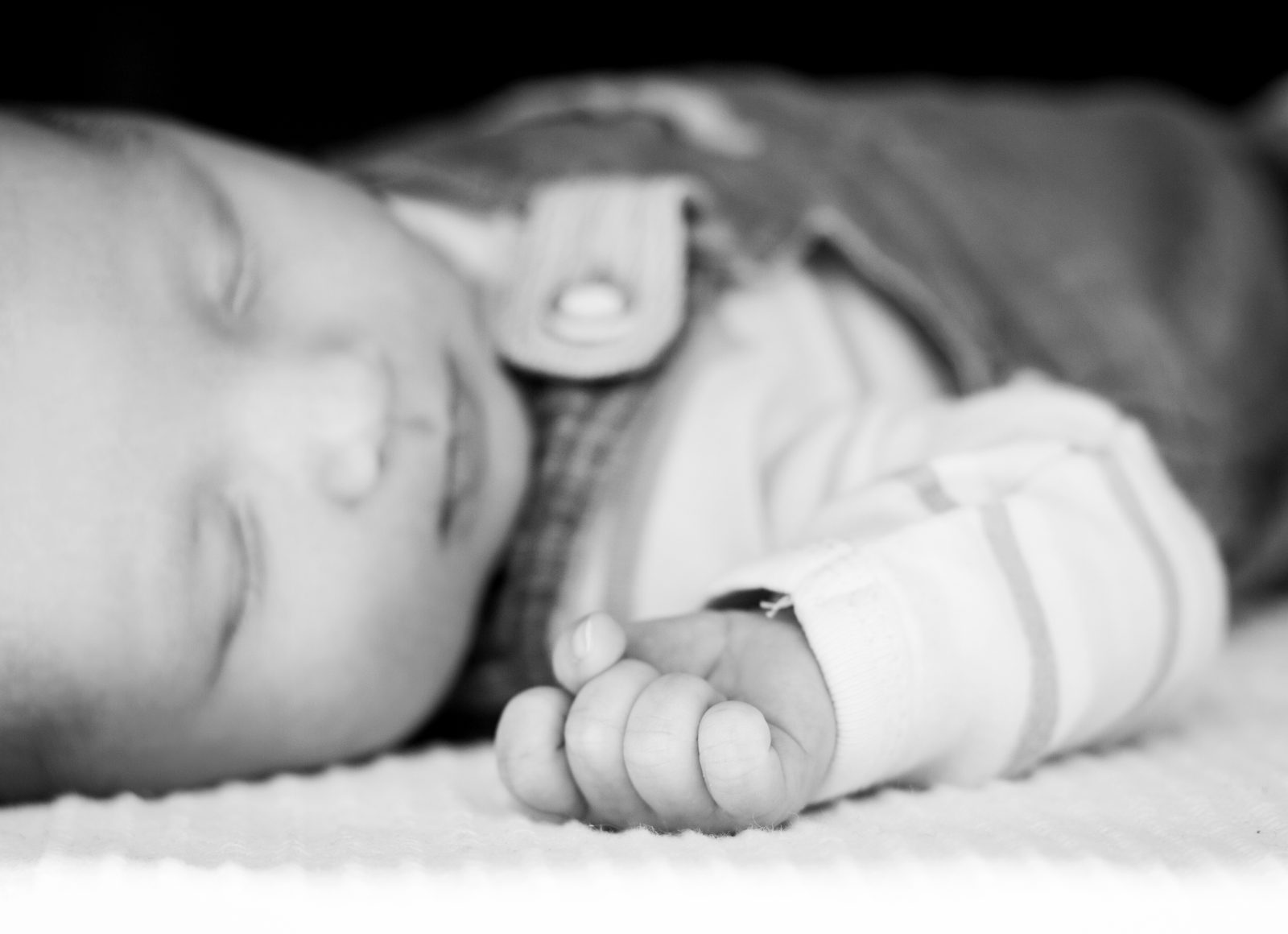 Schlafendes Baby in Schwarz-Weiß mit Hand vor dem Gesicht – Fotostudio in Hamburg