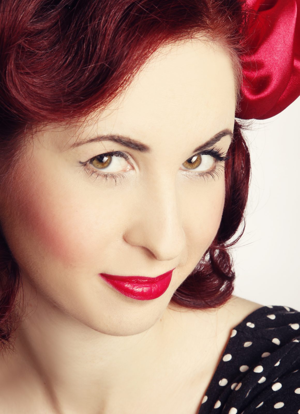 Porträt einer Frau mit rotem Lippenstift und Satinschleife im Pin-up-Stil