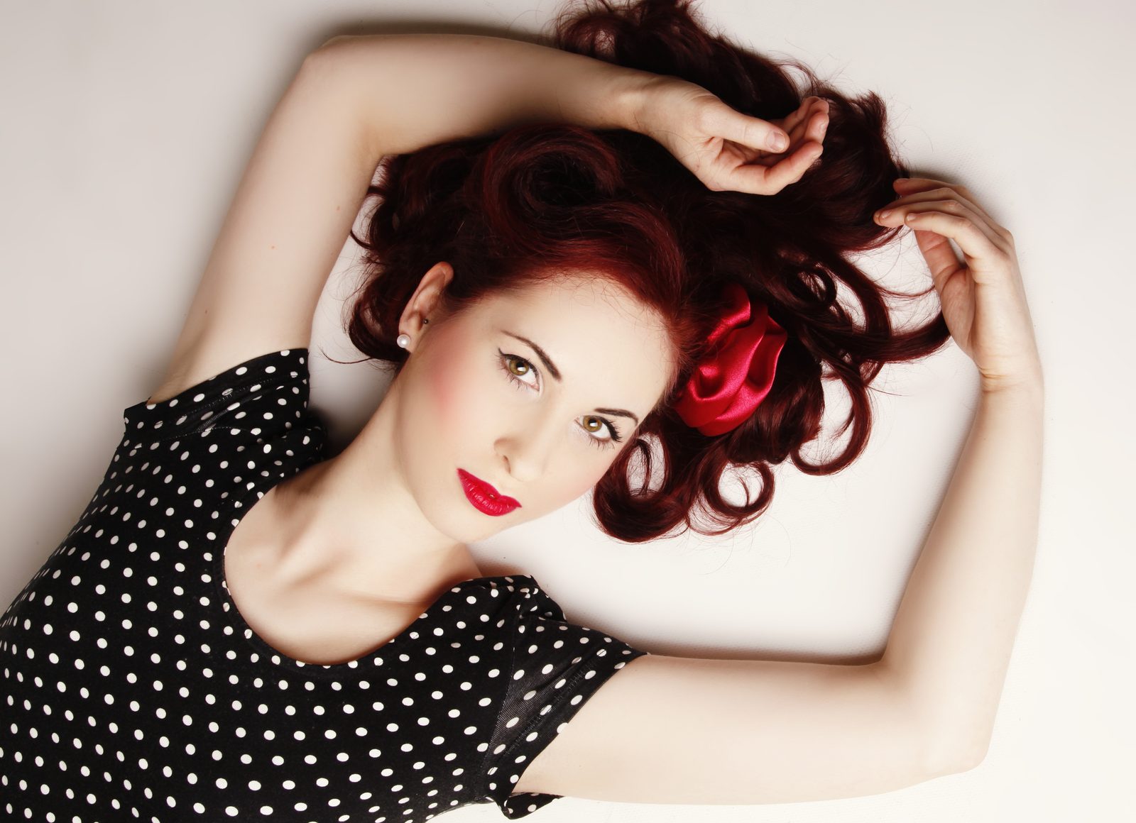 Frau mit roten Locken und Vintage-Make-up liegt vor hellem Hintergrund – Fotostudio in Hamburg