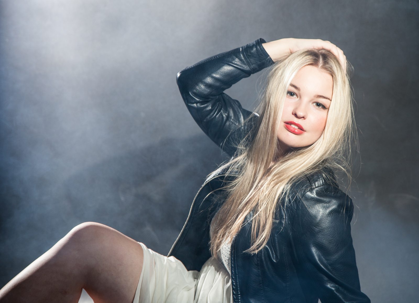 Blonde Frau in Lederjacke posiert vor grauem Hintergrund im Fotostudio in Hamburg