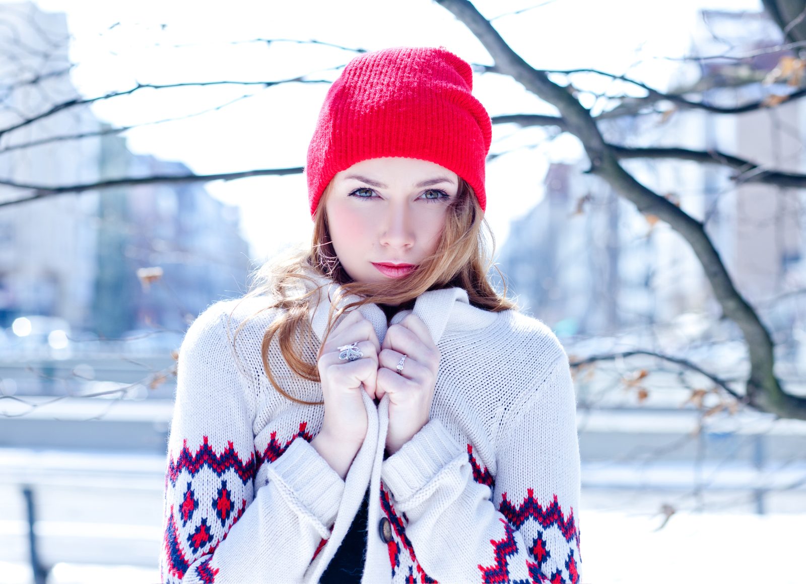 Frau mit roter Mütze und Strickjacke im winterlichen Freien – Porträt