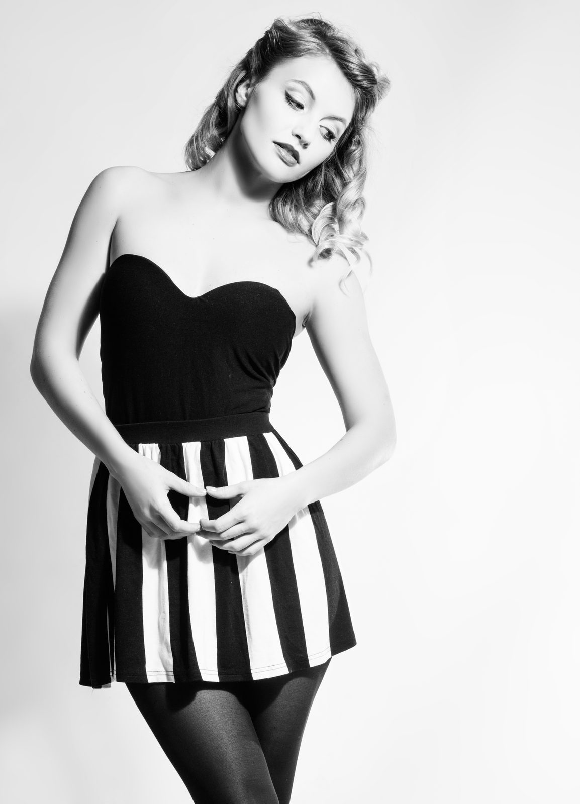 Woman in strapless corset top and striped skirt—black and white studio portrait