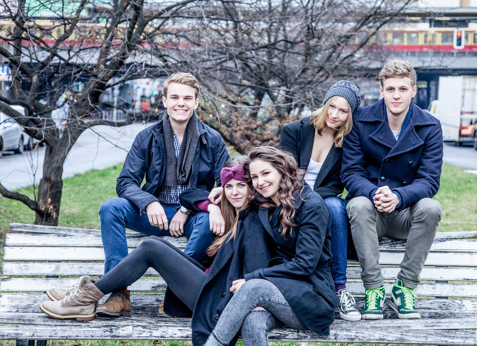 Fünf Freunde sitzen lachend auf einer Bank im Park – Fotoshooting in Hamburg