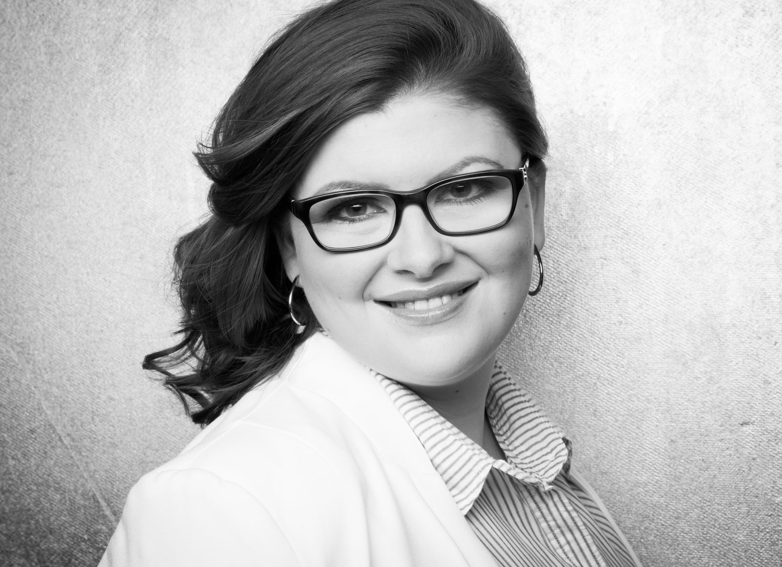 Schwarz-weiß-Porträt einer lächelnden Frau mit Brille – Fotostudio in Hamburg
