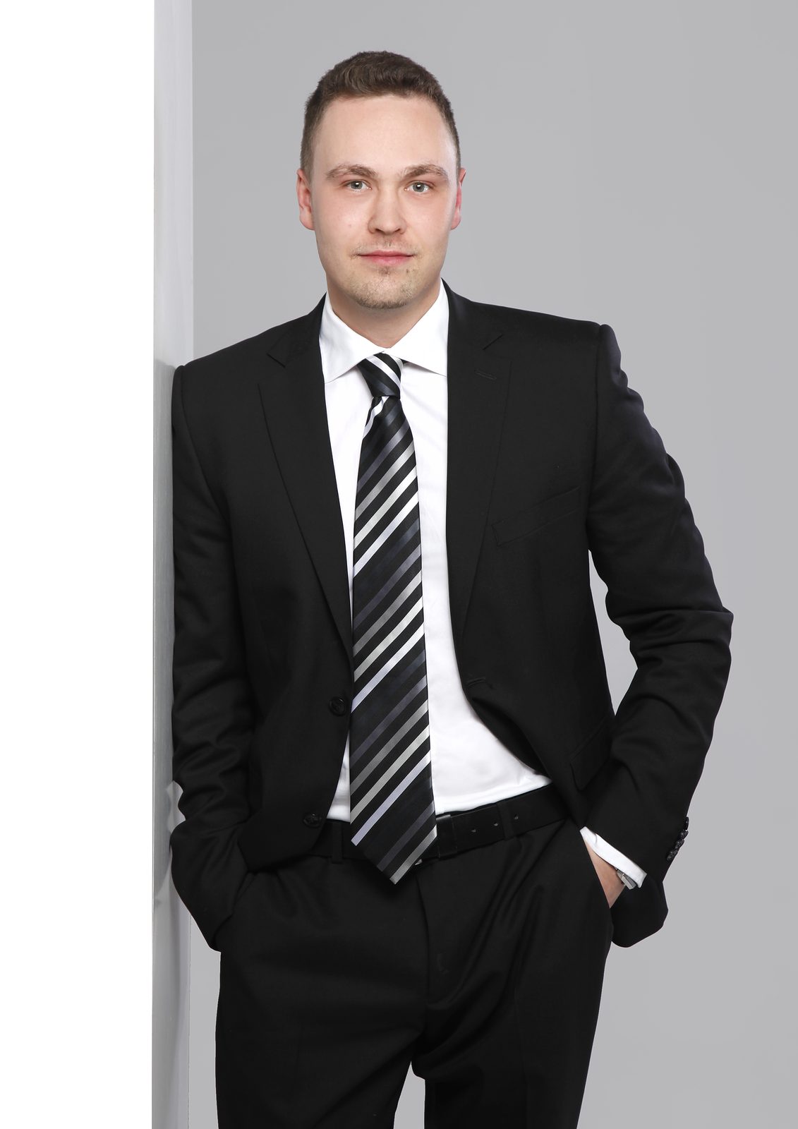 Geschäftsmann im Anzug lehnt an Wand – Business-Porträt im Fotostudio in Hamburg