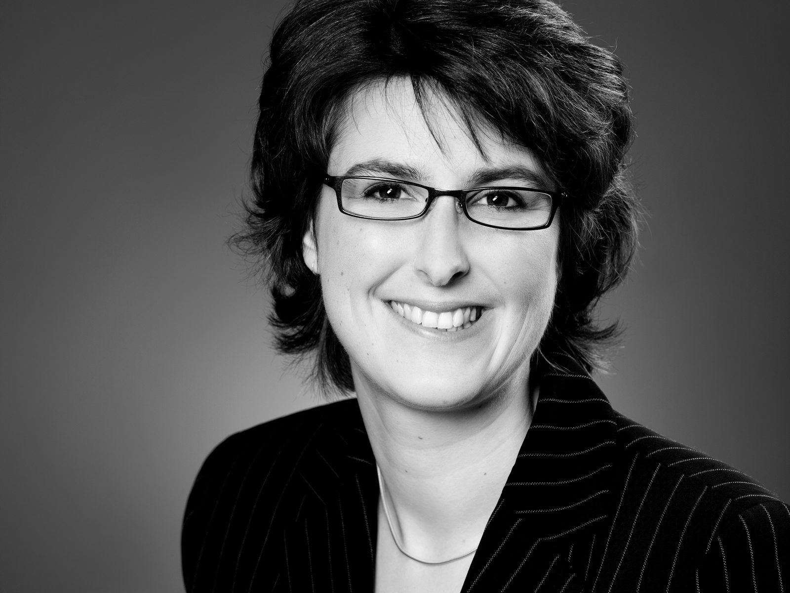 Schwarz-weißes Business-Porträt einer lächelnden Frau mit Brille im Fotostudio in Hamburg