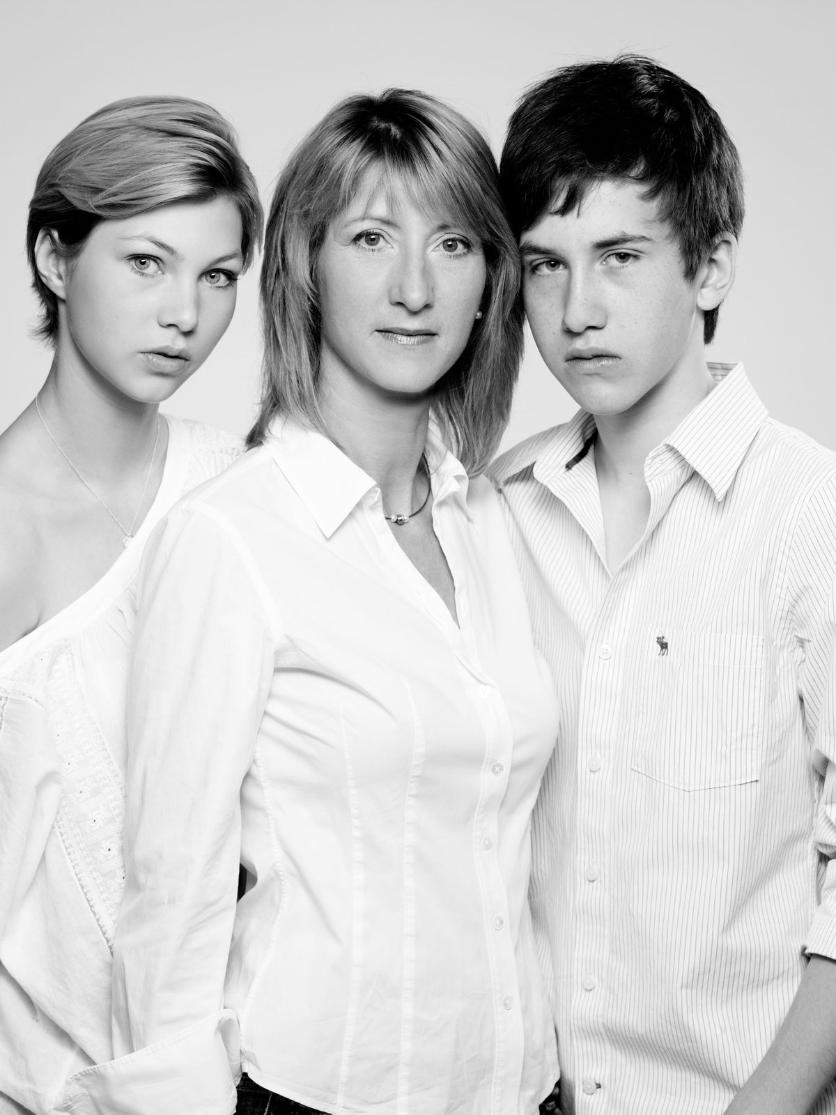Familienporträt in Schwarz-Weiß – drei Personen in weißer Kleidung im Fotostudio in Hamburg