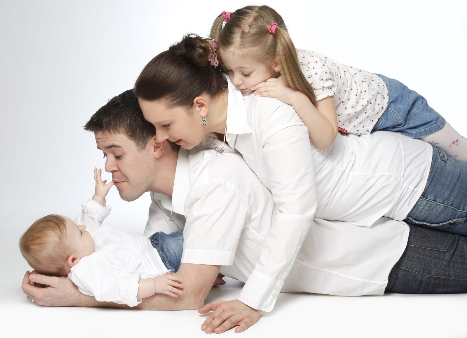 Familie mit Baby und Kind liegt lachend übereinander bei einem Fotoshooting in Hamburg