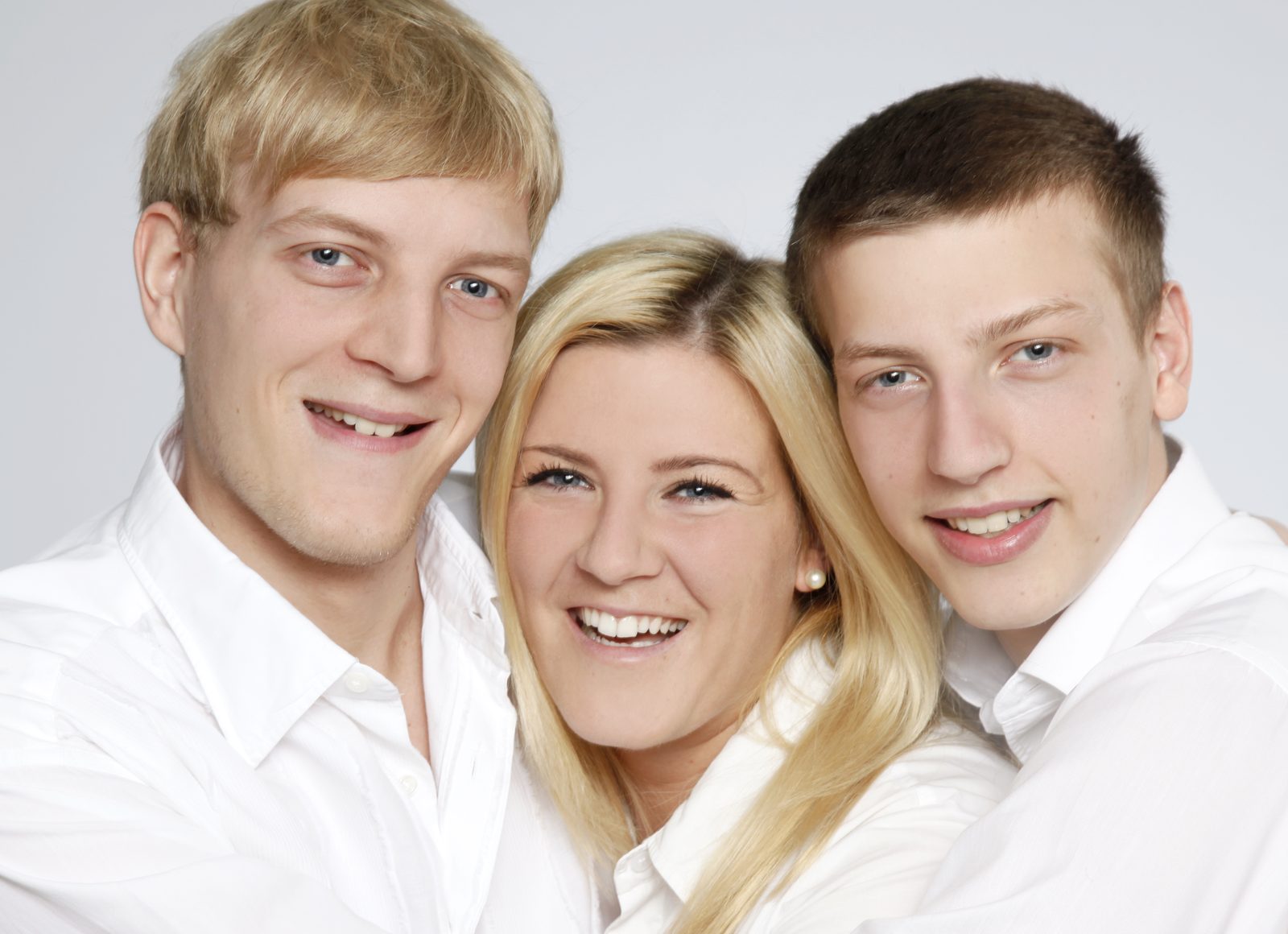 Drei lächelnde junge Erwachsene in weißen Hemden vor hellem Hintergrund – Fotoshooting in Hamburg