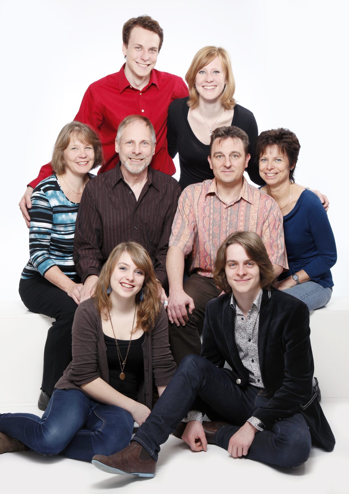 Extended family of eight smiling together in a bright Hamburg photo studio