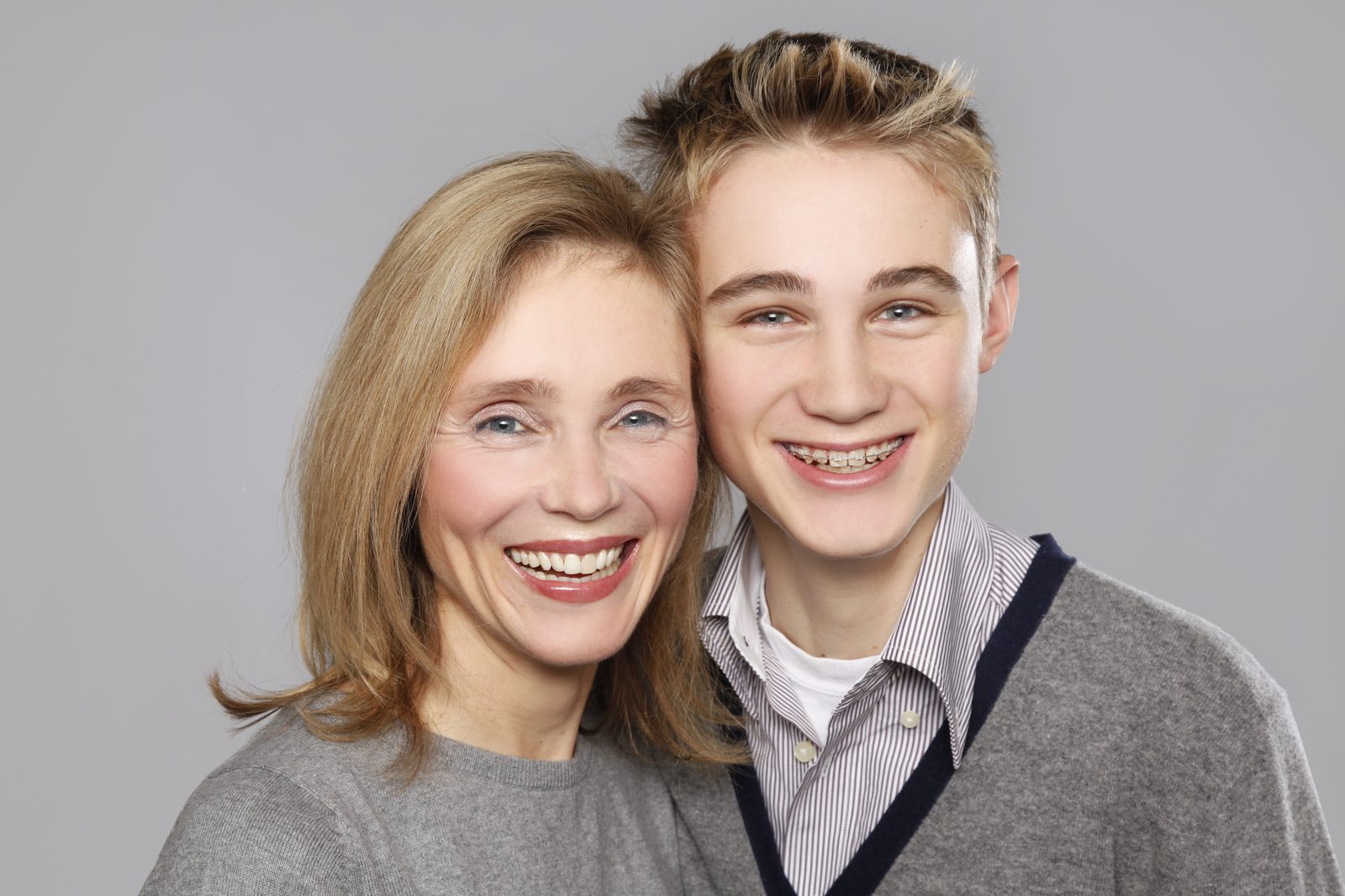 Mutter und Sohn lächeln eng aneinander im Fotostudio in Hamburg
