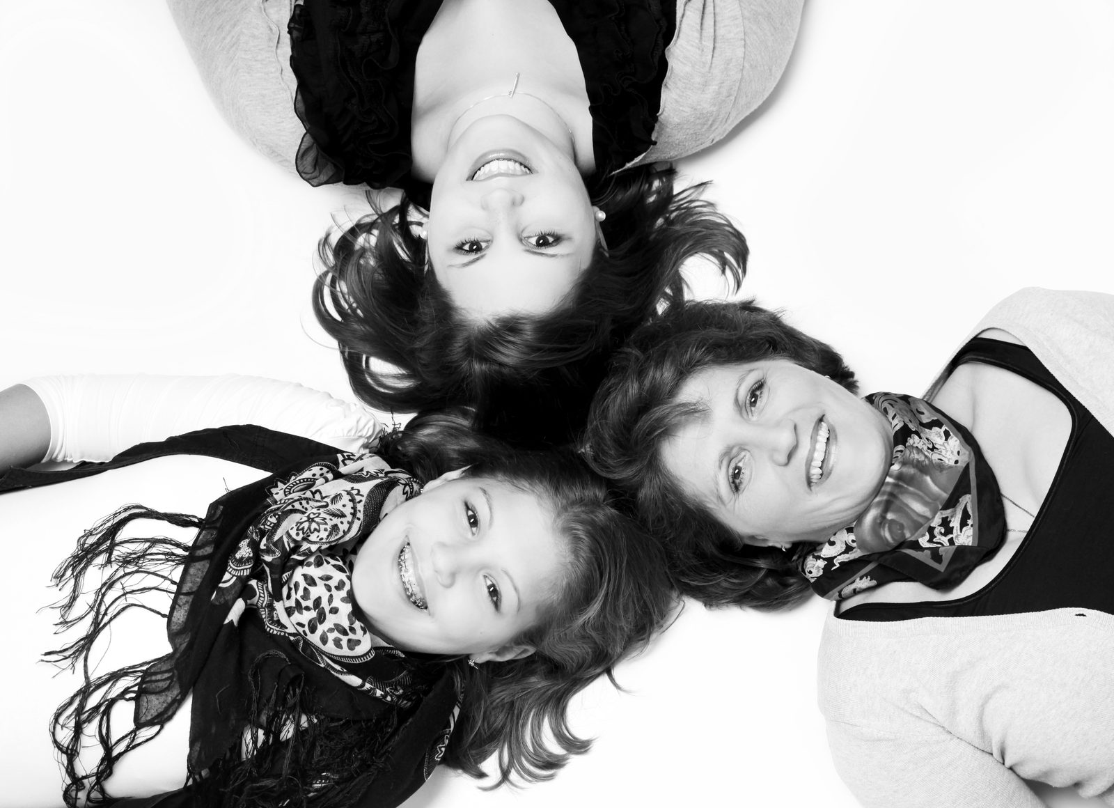 Three generations lying head to head, smiling—black-and-white portrait
