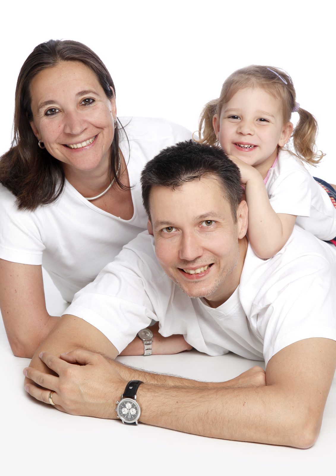 Family with young daughter laughing together against a bright backdrop