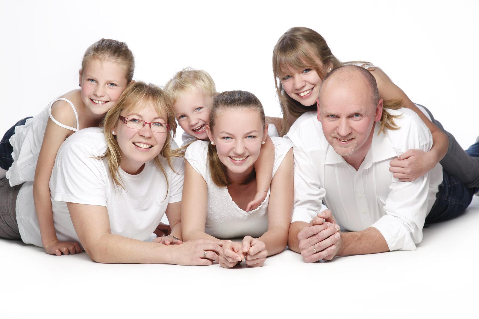 Familie mit sechs Personen liegt lachend zusammen im Fotostudio in Hamburg