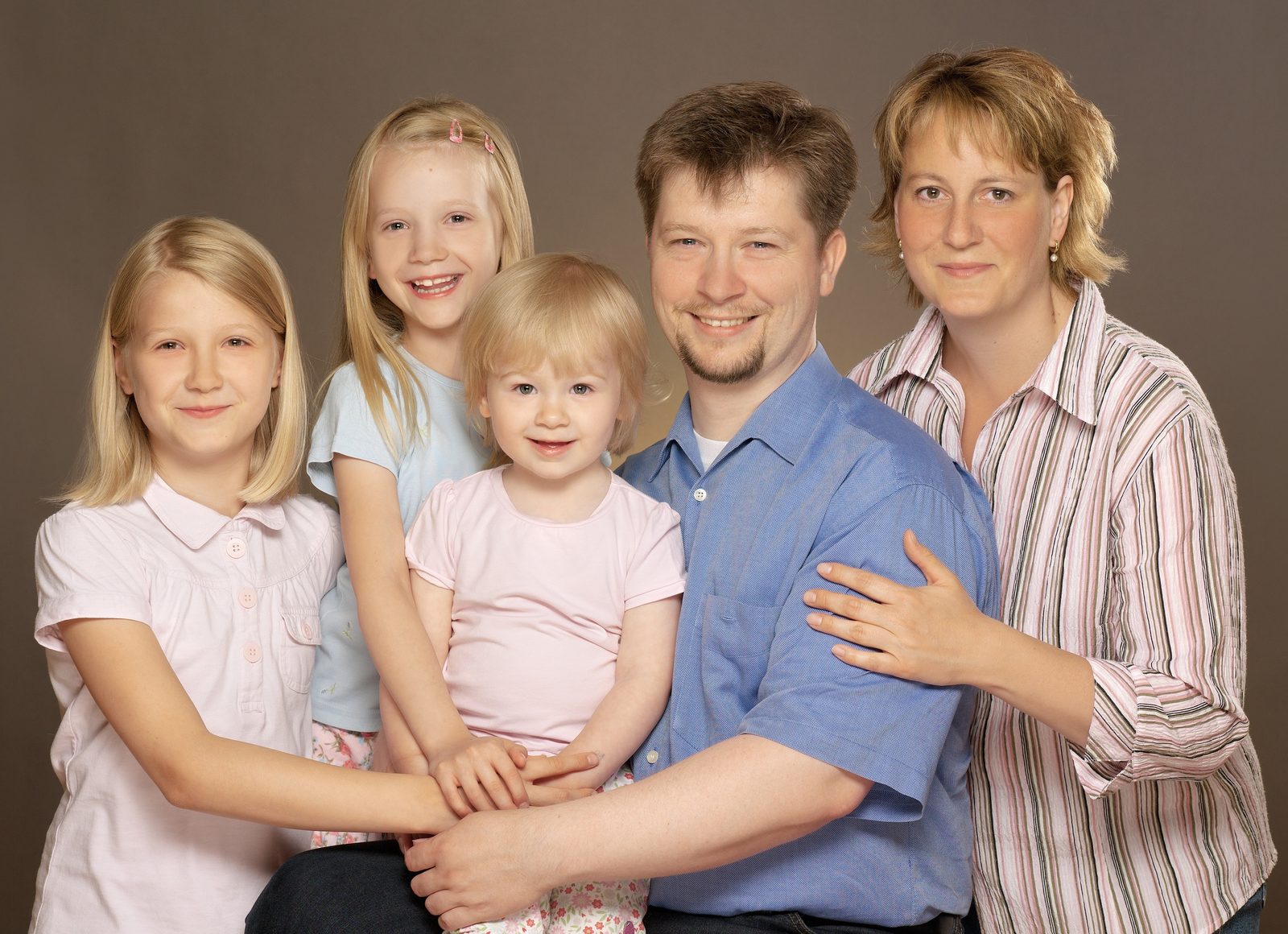 Familienfoto mit Eltern und drei Töchtern vor braunem Hintergrund im Fotostudio in Hamburg