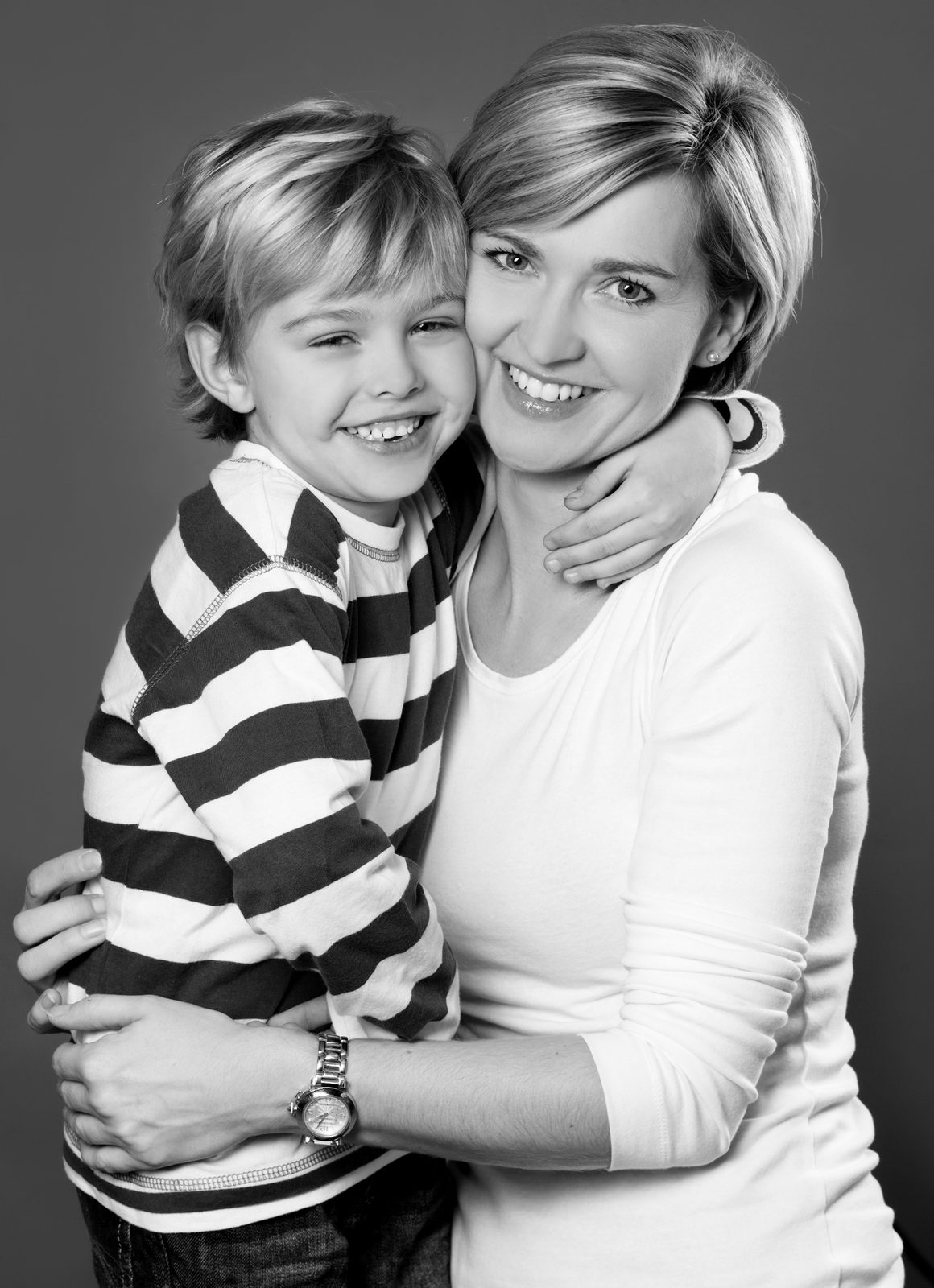 Mother and son embracing and laughing — black-and-white studio portrait