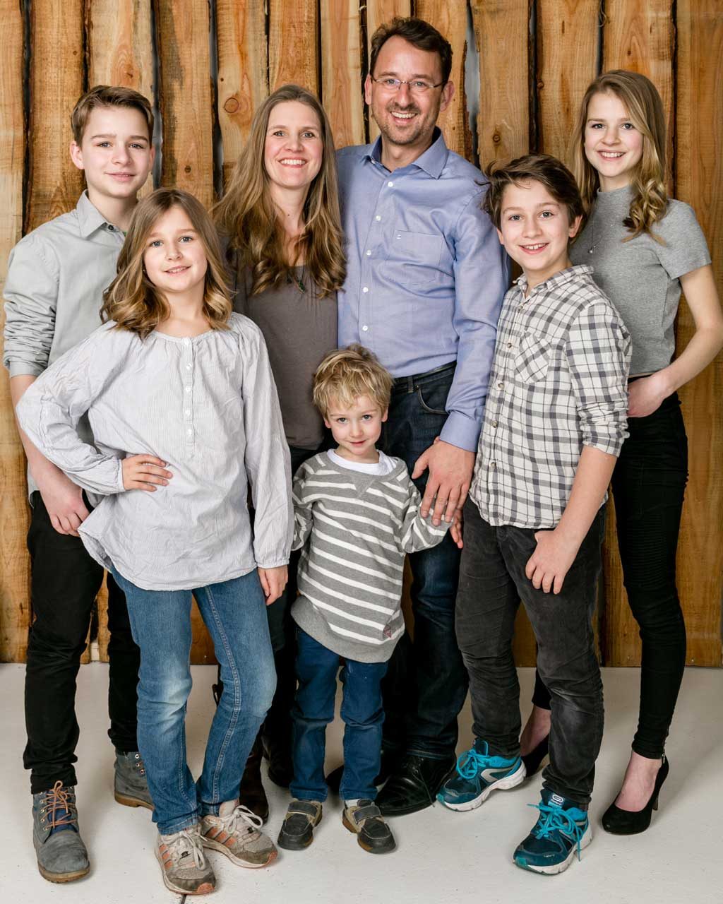 Familienporträt mit Eltern und fünf Kindern vor Holzwand – Fotostudio in Hamburg