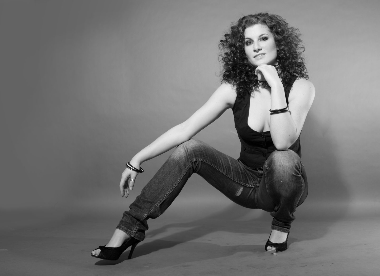 Frau mit Locken posiert kniend im Fotostudio in Hamburg, Schwarz-Weiß-Aufnahme