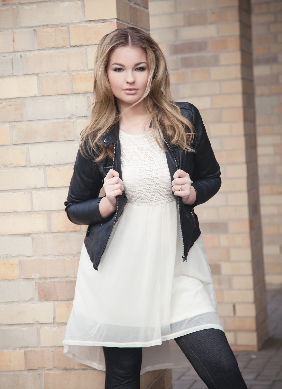Frau in weißem Kleid und Lederjacke vor Backsteinwand – Fotoshooting in Hamburg