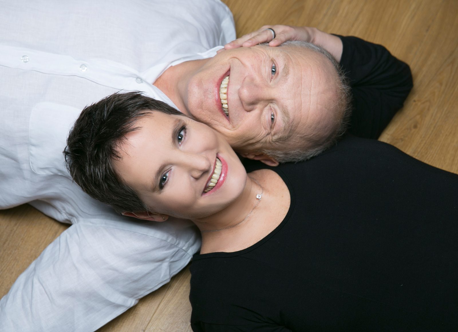 Mann und Frau liegen lachend Kopf an Kopf auf Holzboden – Fotoshooting in Hamburg