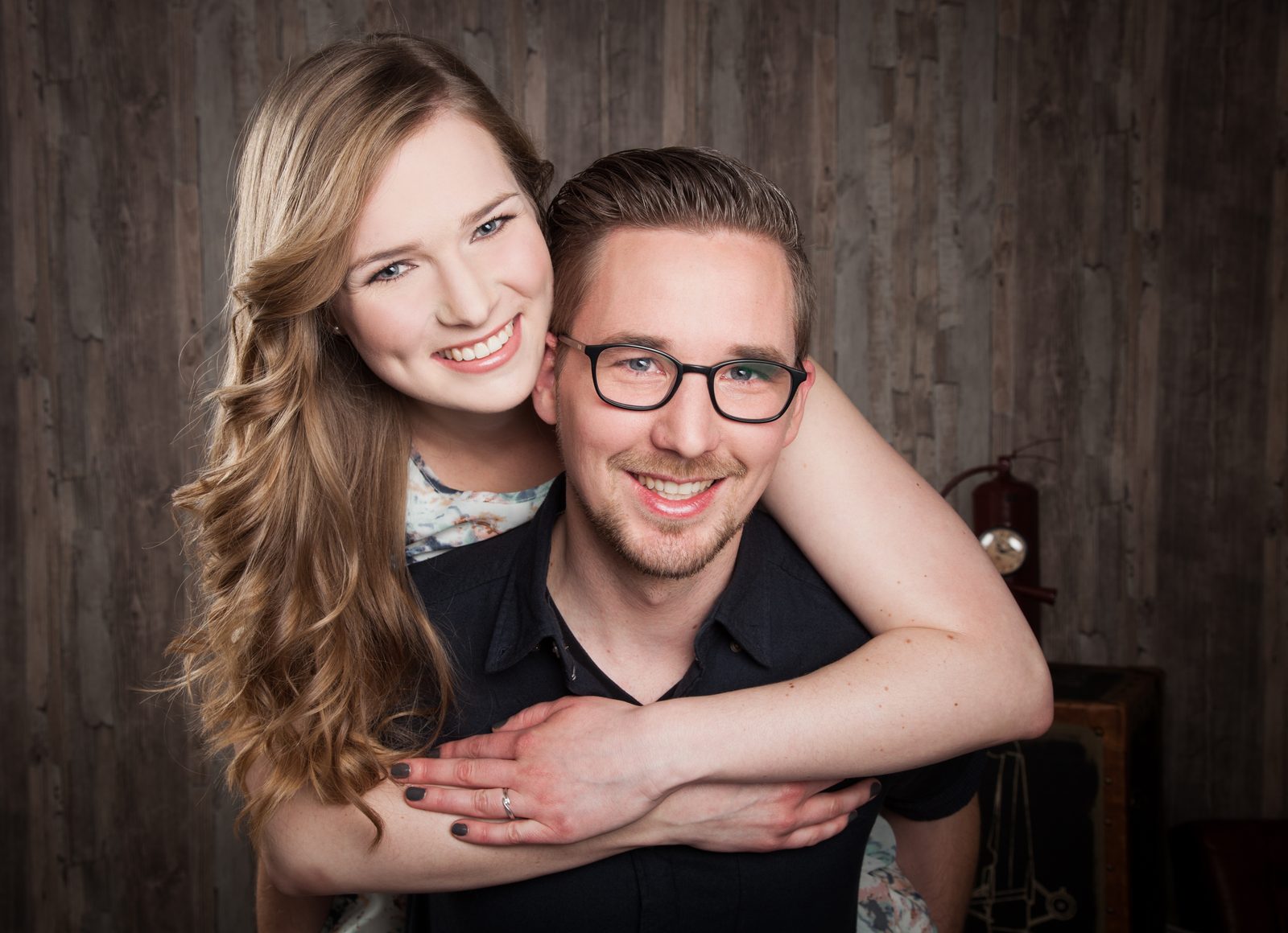 Lächelndes Paar umarmt sich vor Holzwand – Fotostudio in Hamburg
