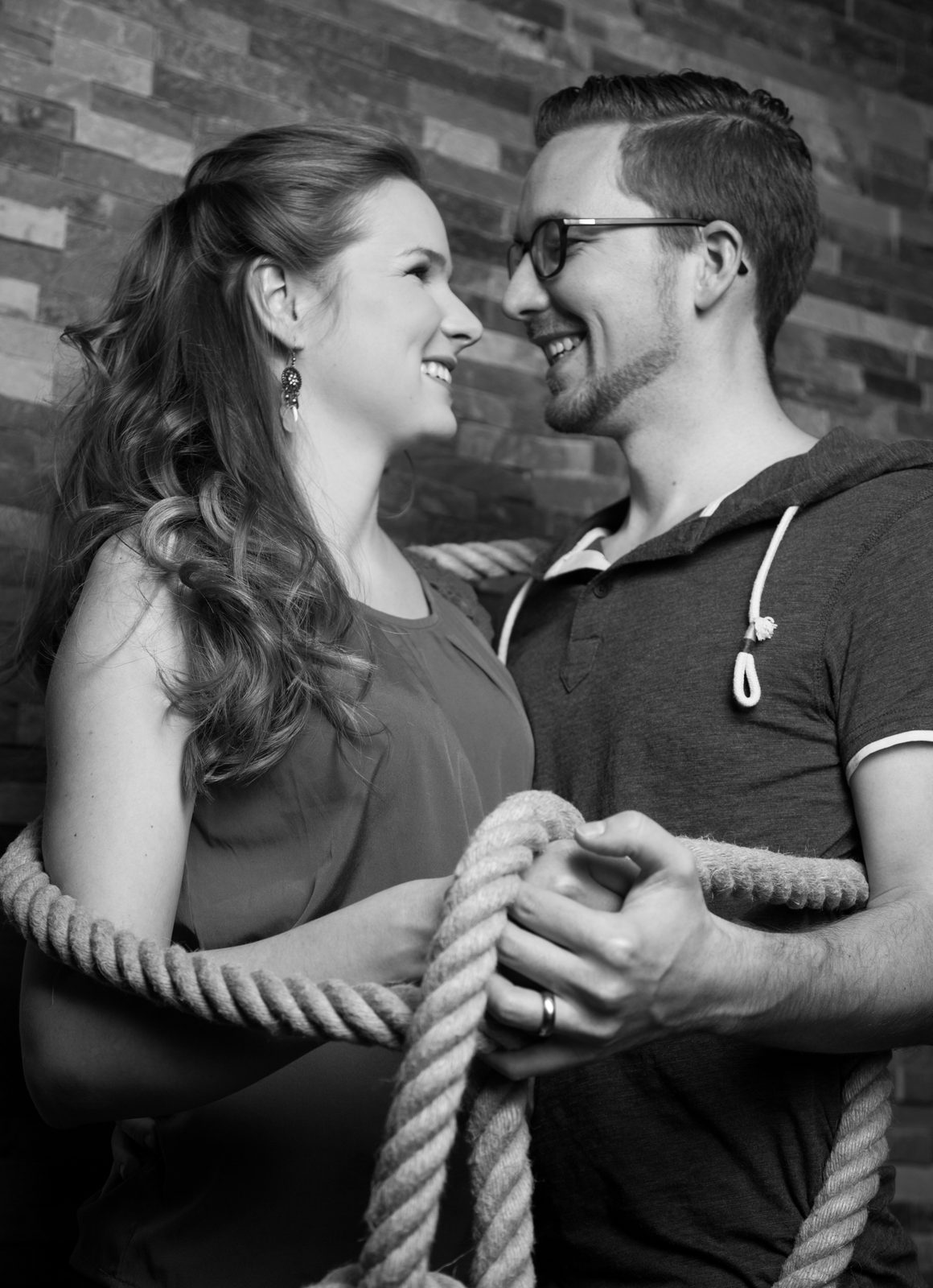 Lächelndes Paar hält gemeinsam ein Seil, Schwarz-Weiß-Fotoshooting in Hamburg