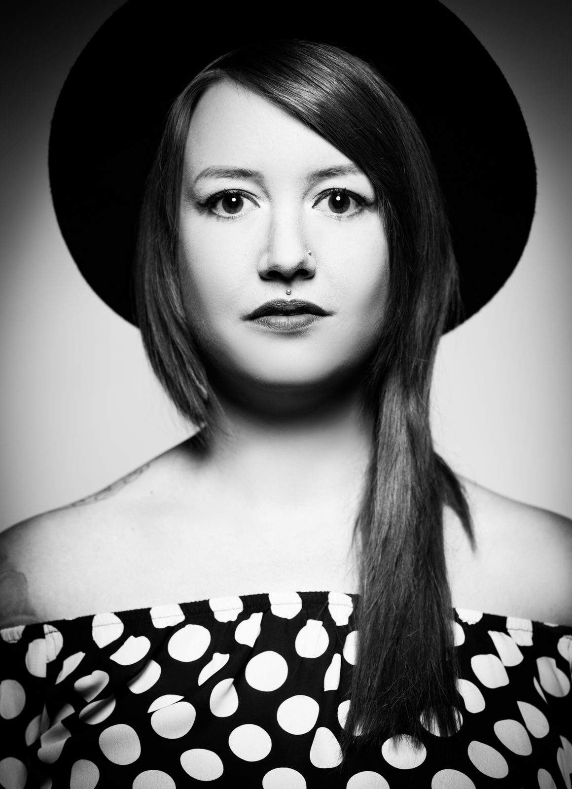 Schwarz-weiß-Porträt einer Frau mit Hut und Septum-Piercing im Fotostudio in Hamburg