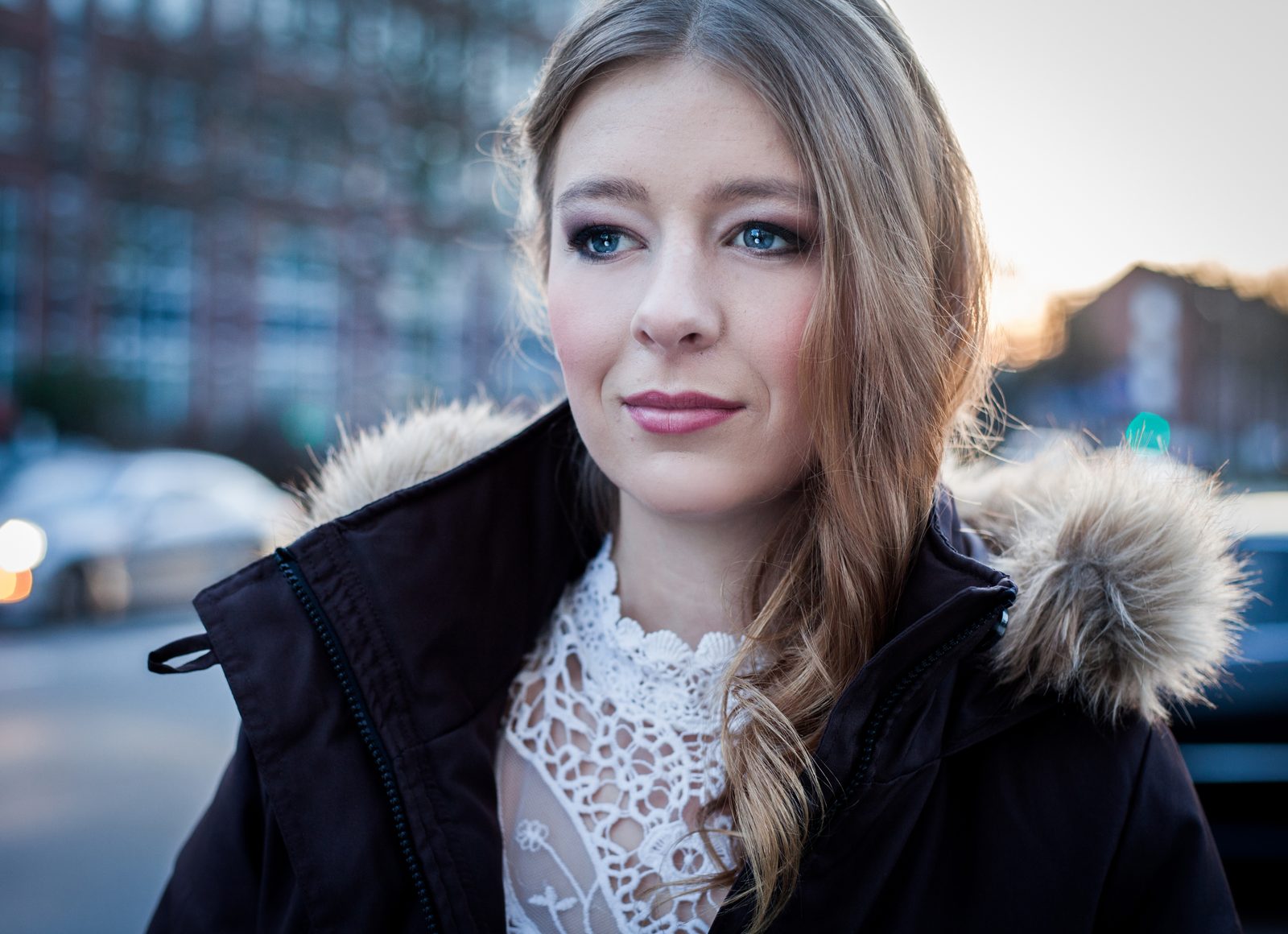Frau im Winterlook mit Fellkapuze – Porträt im Freien bei Dämmerlicht