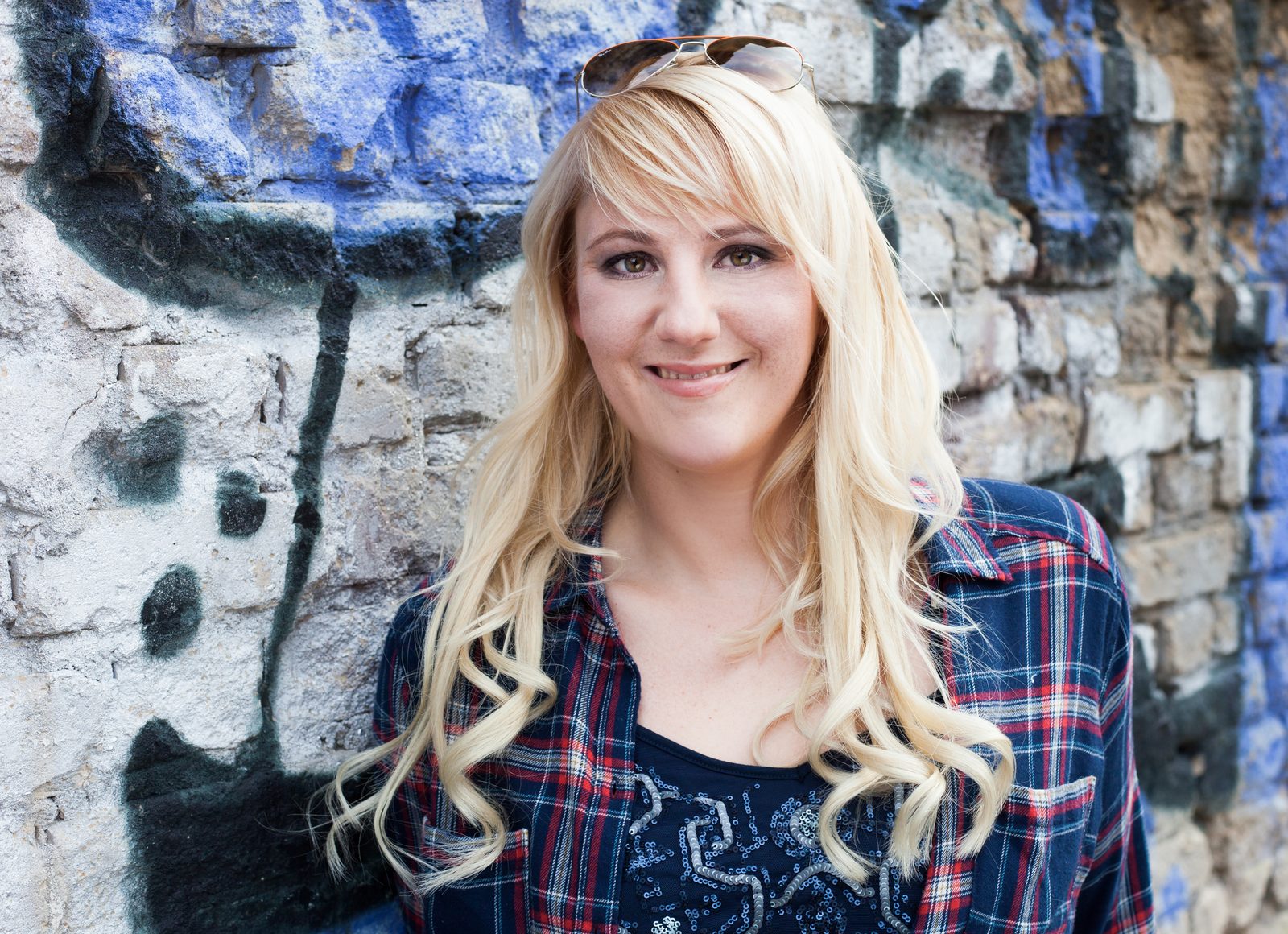 Smiling blonde woman in front of a painted stone wall — portrait session in Hamburg
