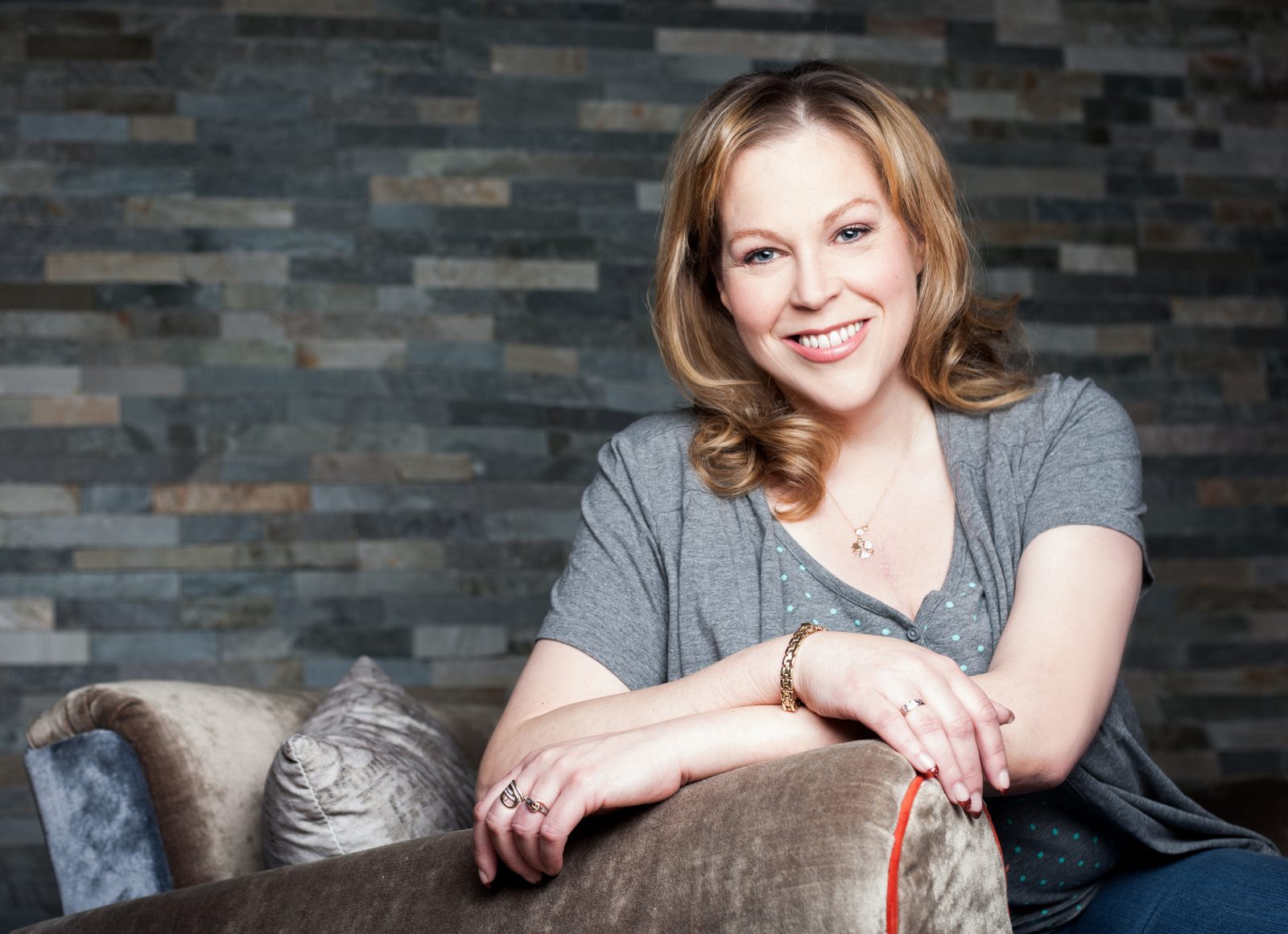 Smiling woman with blonde hair relaxes on a sofa indoors