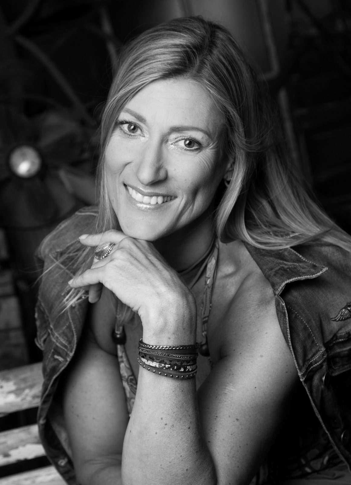 Black-and-white portrait of a smiling woman in a denim vest — studio in Hamburg