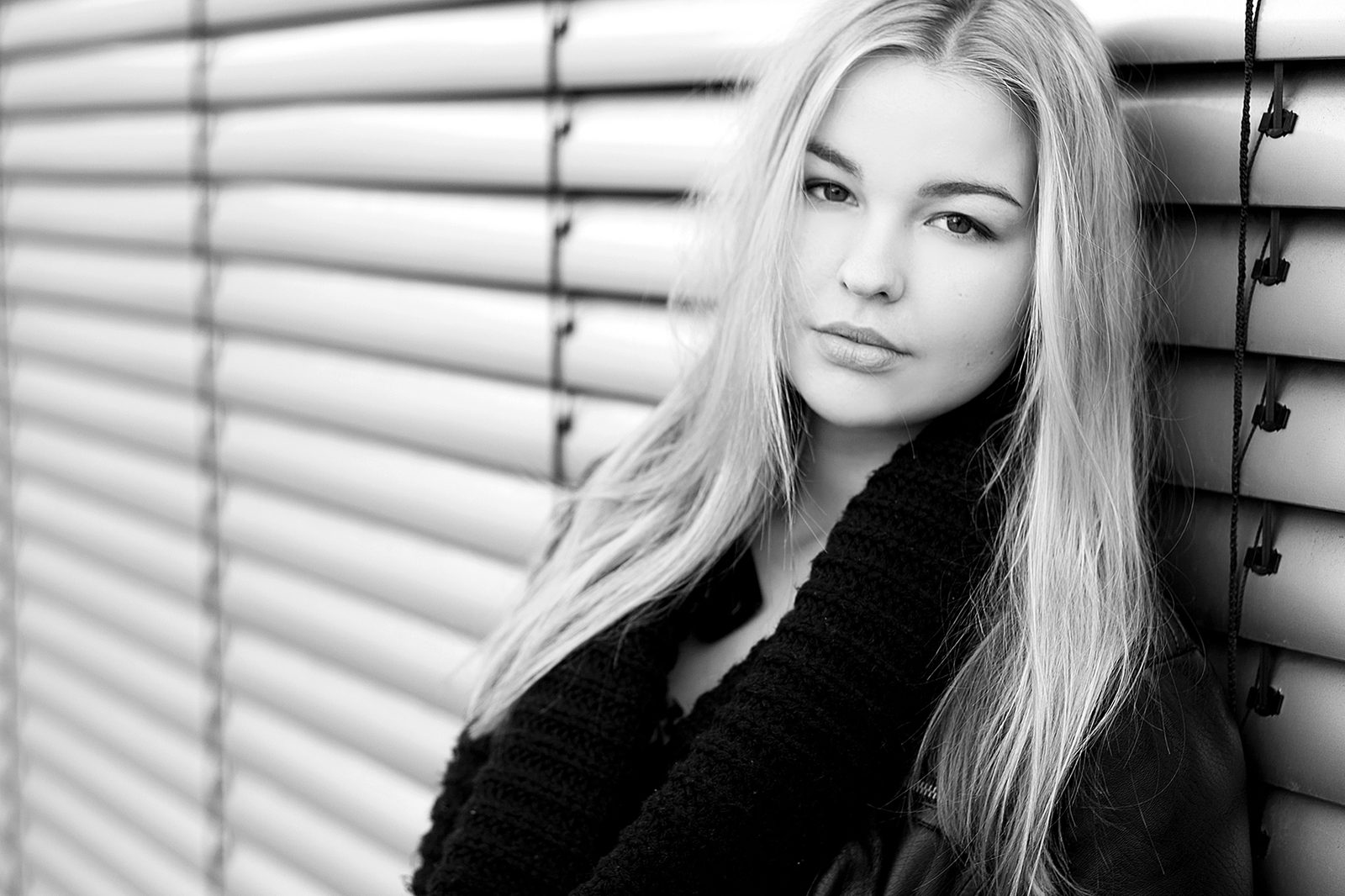 Black-and-white portrait of a young woman in front of blinds—studio in Hamburg