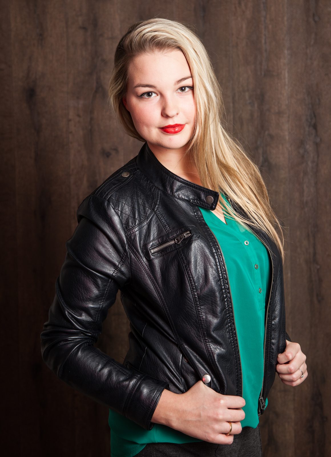 Frau in schwarzer Lederjacke und grüner Bluse vor Holzwand – Fotostudio in Hamburg