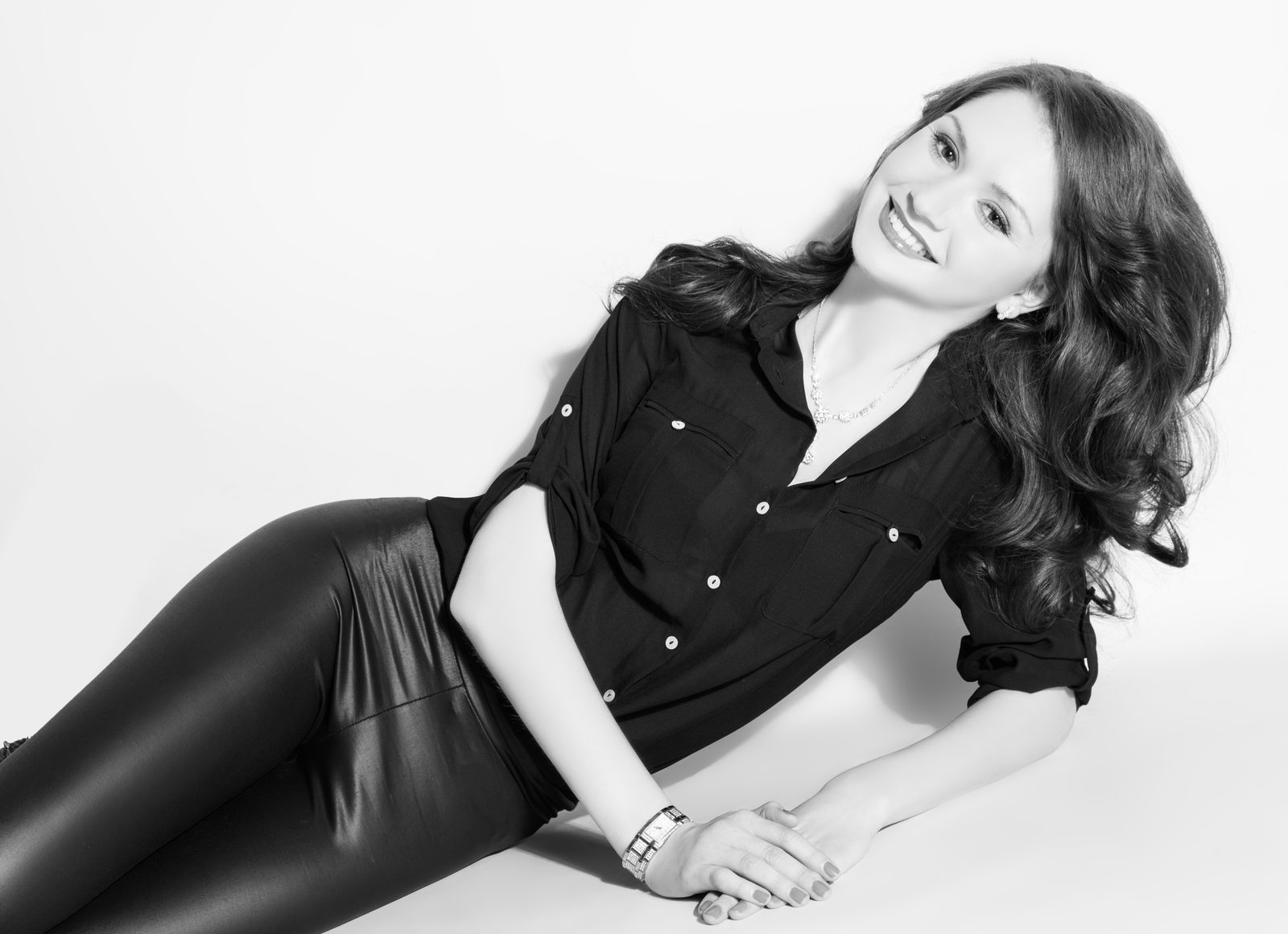 Lächelnde Frau in schwarzer Bluse liegt im Fotostudio in Hamburg – Schwarz-Weiß-Porträt