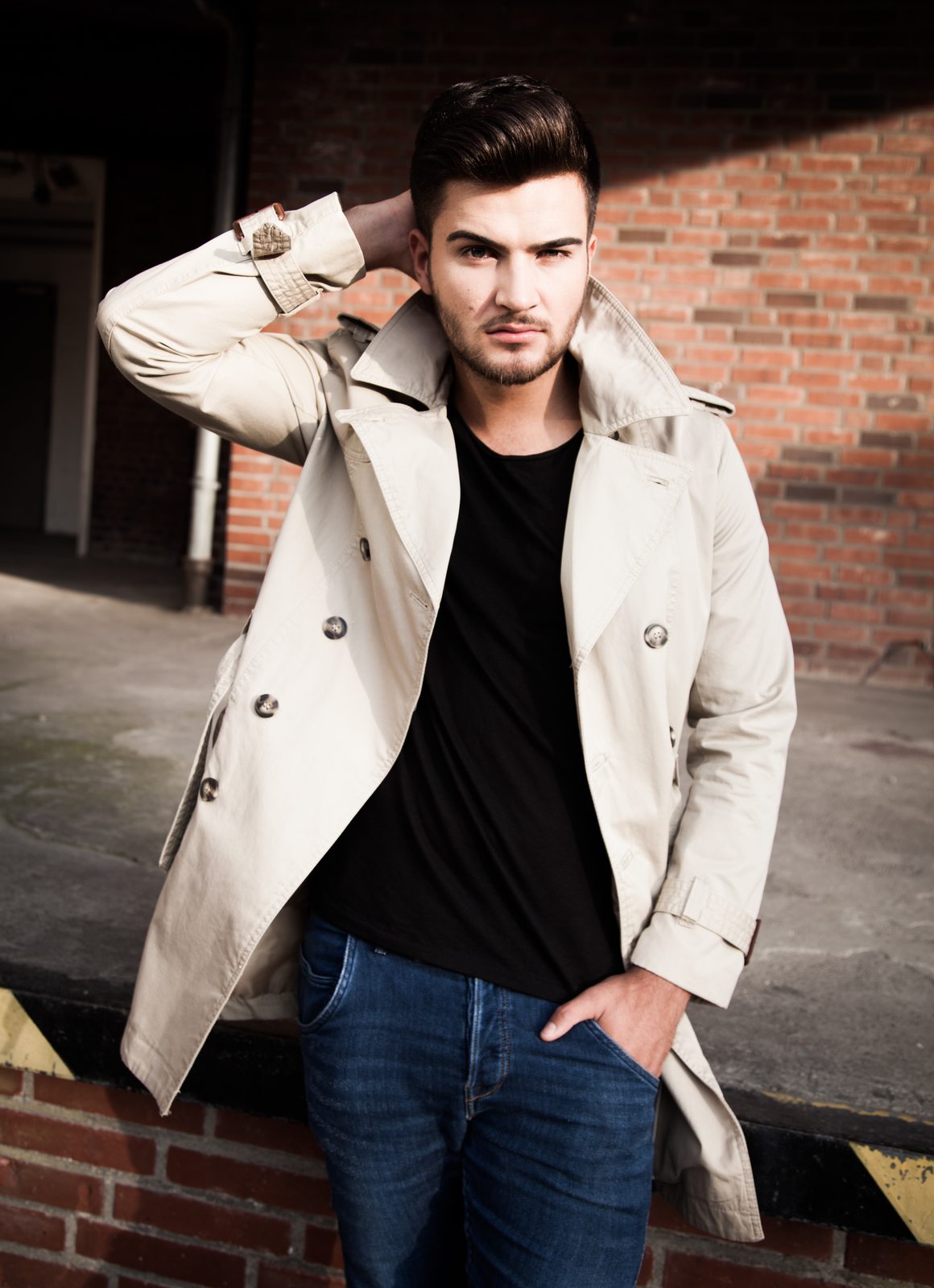 Mann im Trenchcoat posiert vor Backsteinwand – Fotoshooting in Hamburg