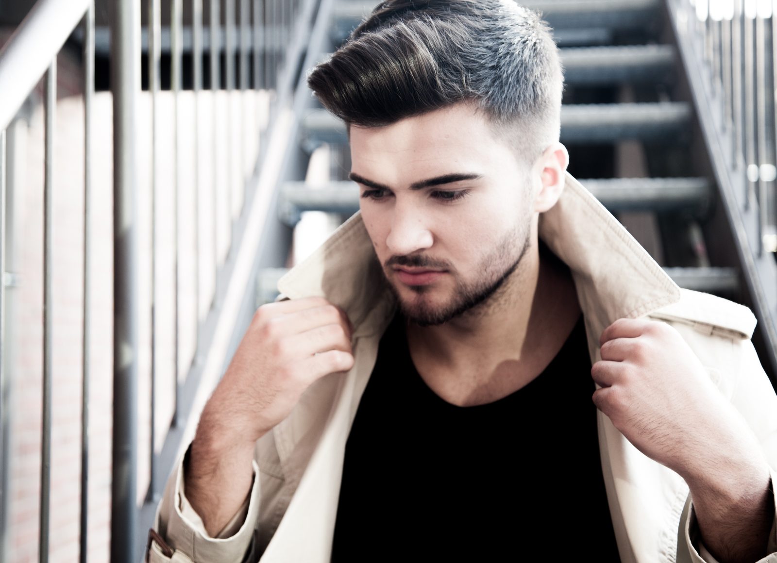 Man with beard adjusts coat collar on a metal staircase — Hamburg photo studio