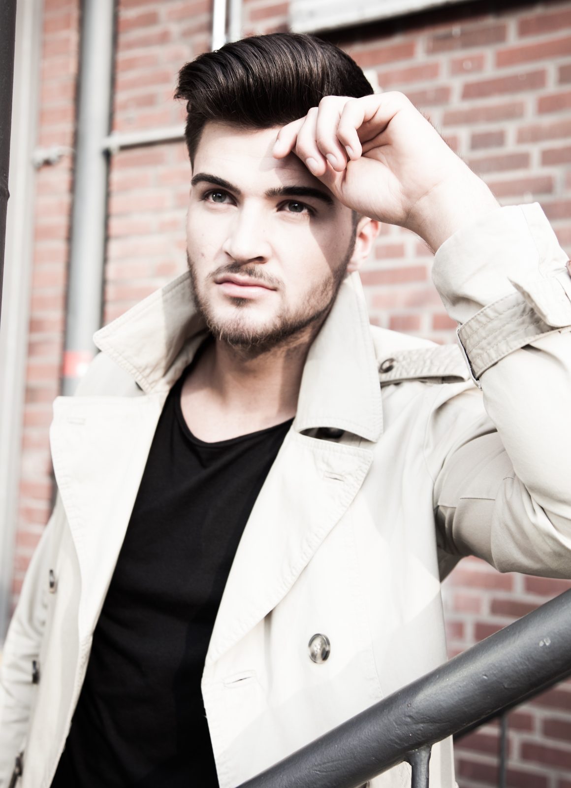 Man in trench coat posing against a brick wall — portrait shot