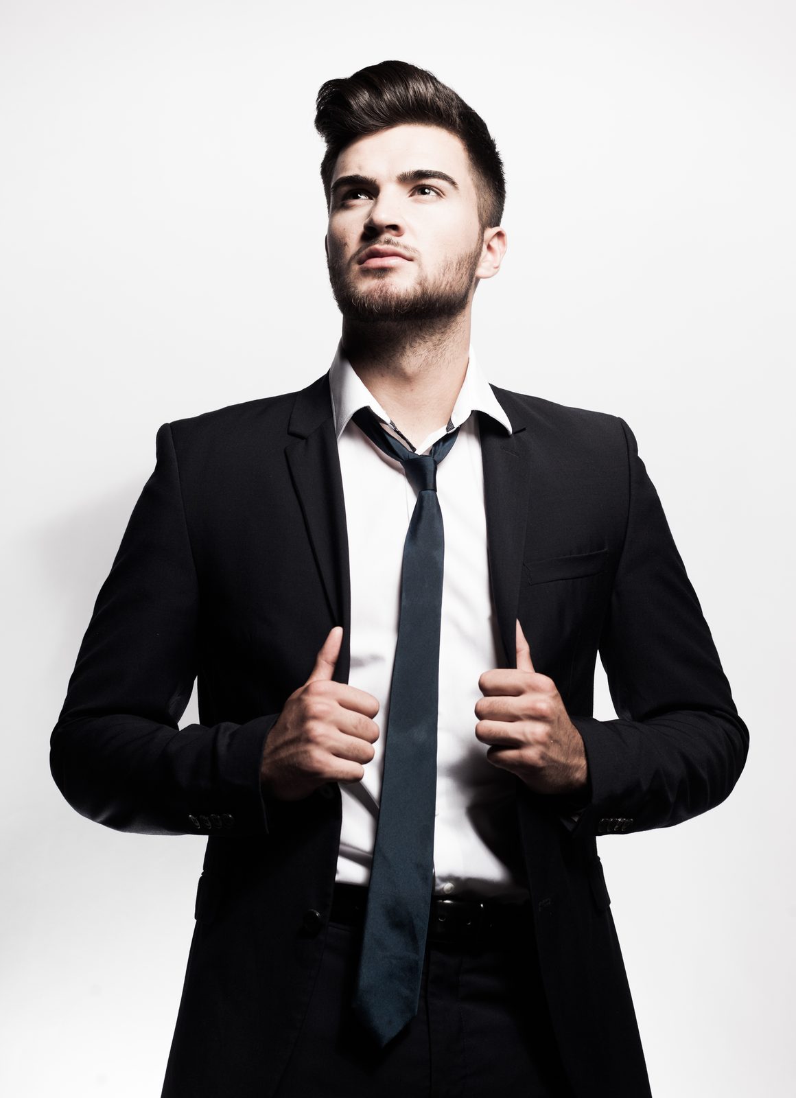 Man in a suit and tie posing confidently in a bright studio setting