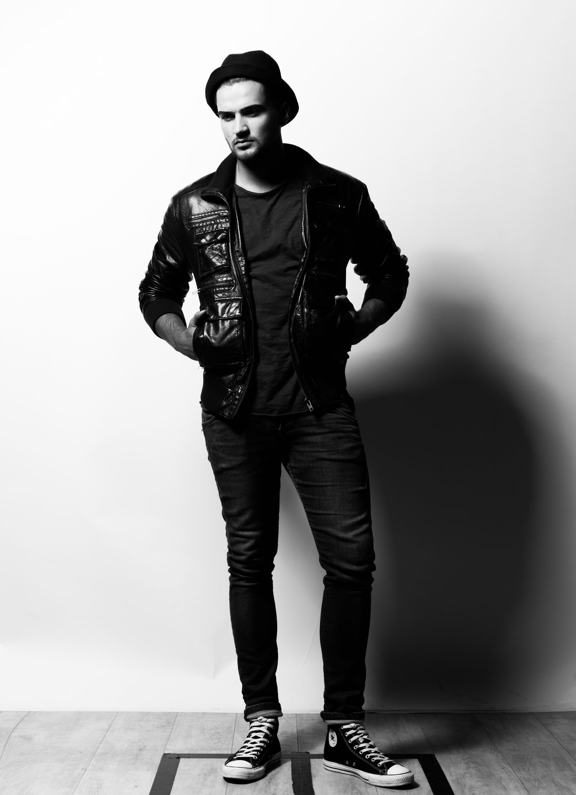 Mann in Lederjacke und Beanie posiert in Schwarz-Weiß im Fotostudio in Hamburg